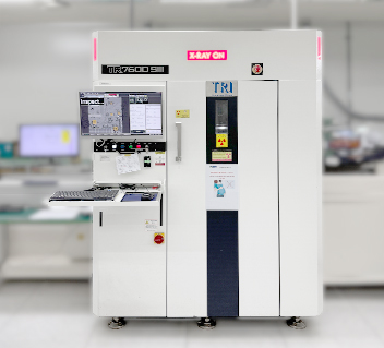 Industrial X-ray machine with warning signs and a small window on a blurred lab background.