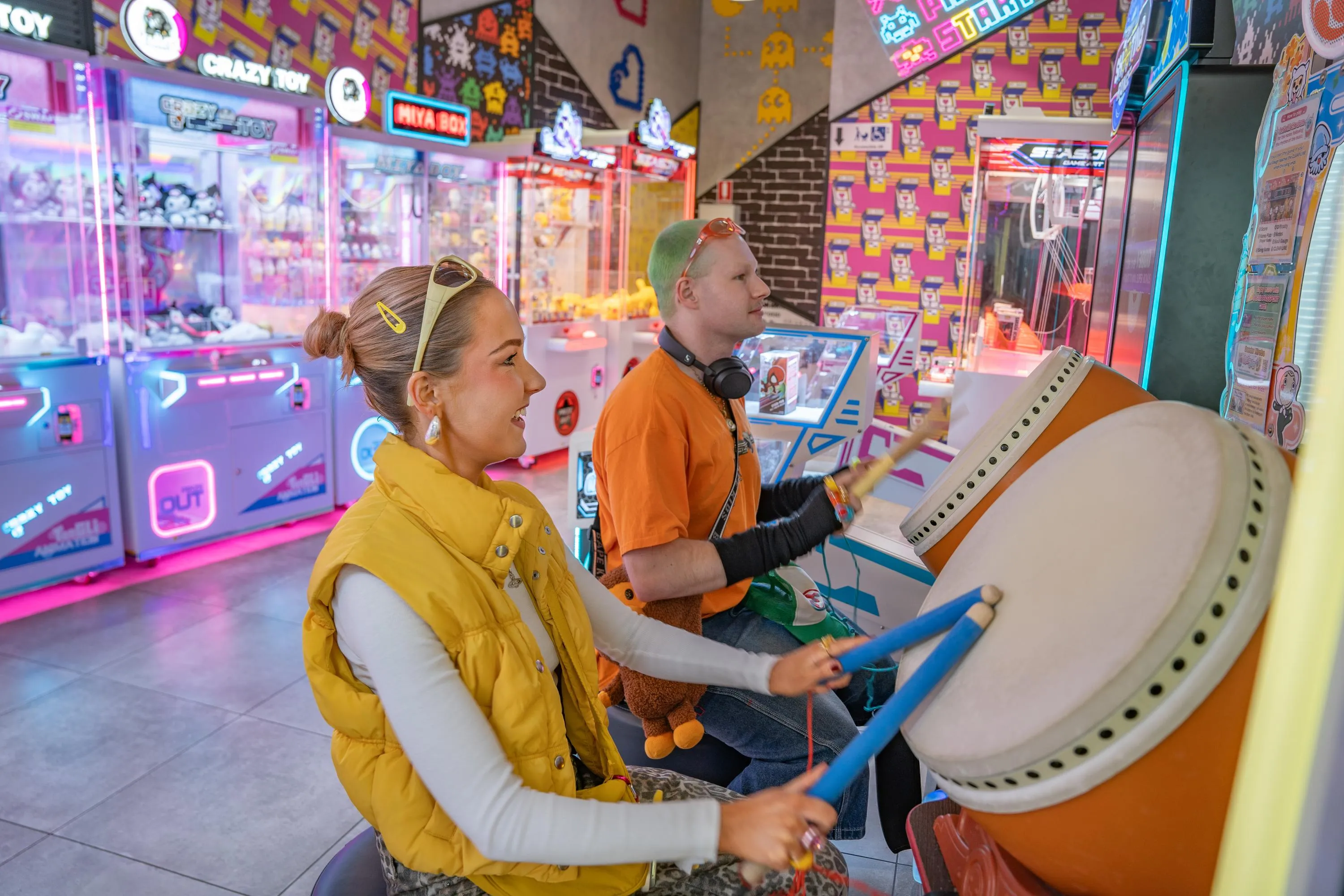 Two adults playing a Japanese taiko drum arcade machine at KOKO Amusement