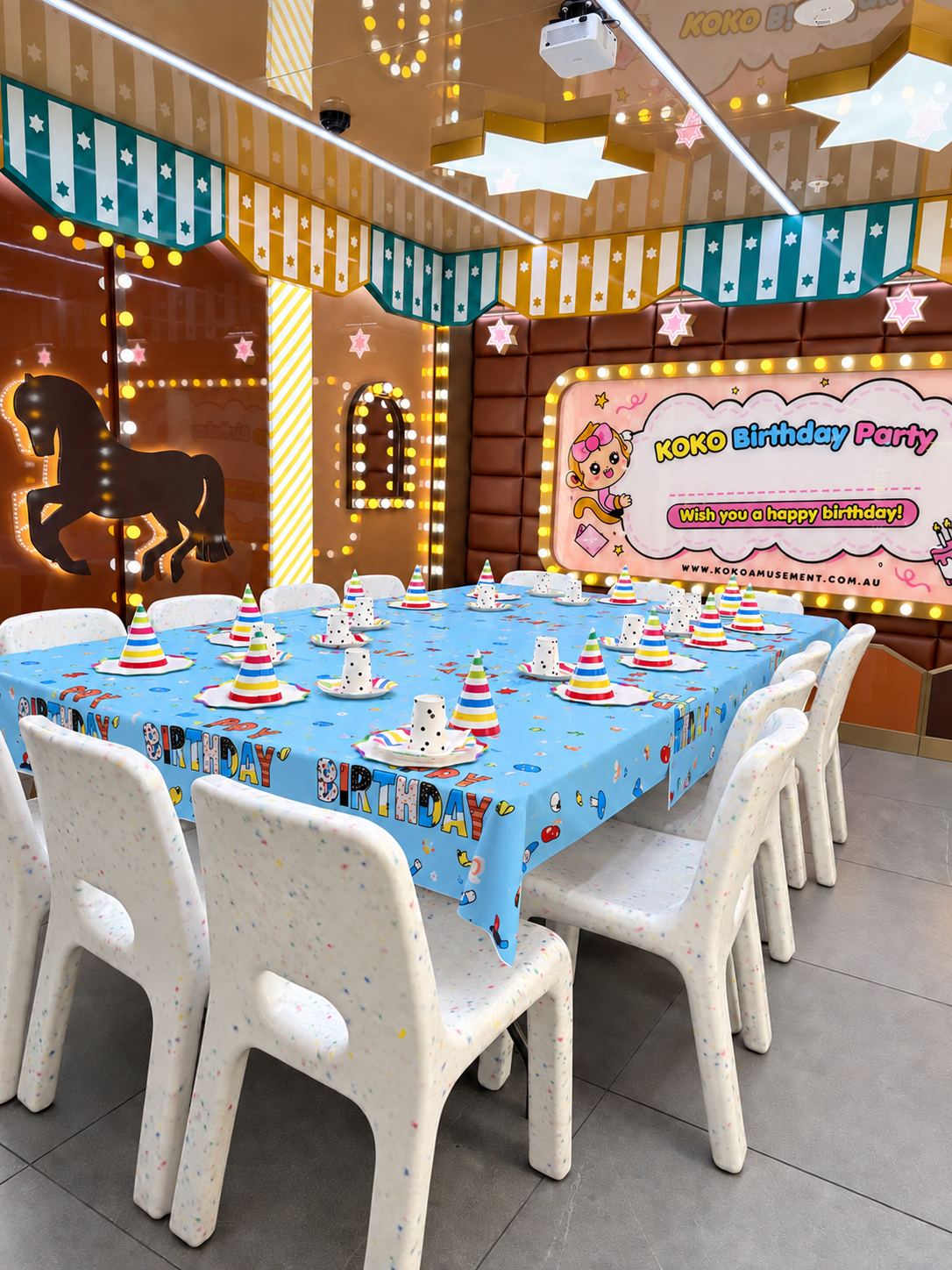Private birthday party room at KOKO Amusement Town Hall with a neon Let's Go Party sign and a set table for guests