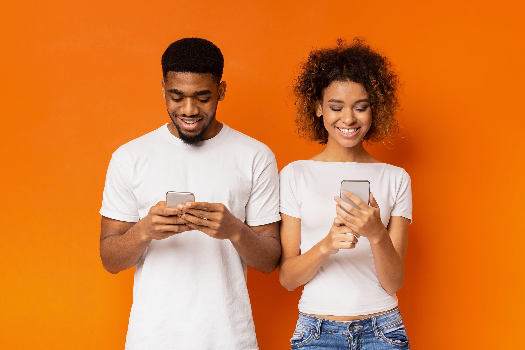 young black couple happily browsing their phones