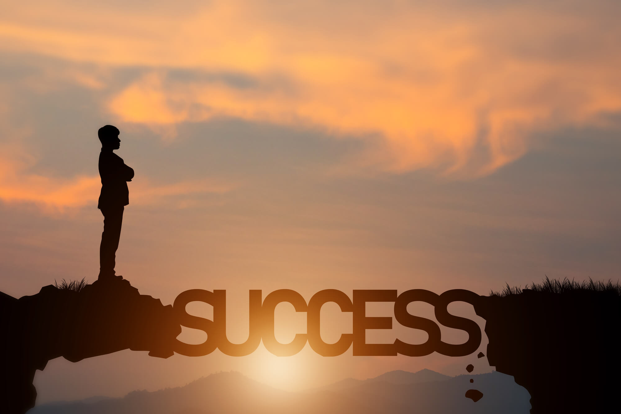 businessman standing on cliff with the word success bridging the way