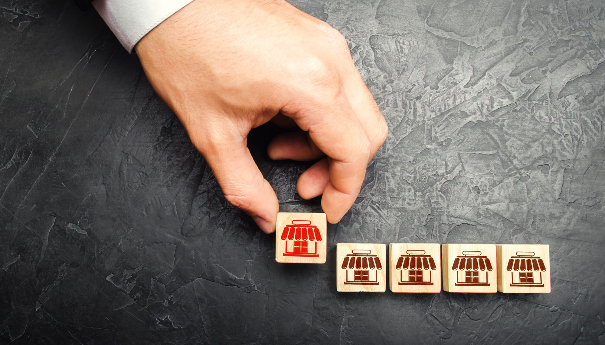 hand holding a block with a store icon next to similar blocks