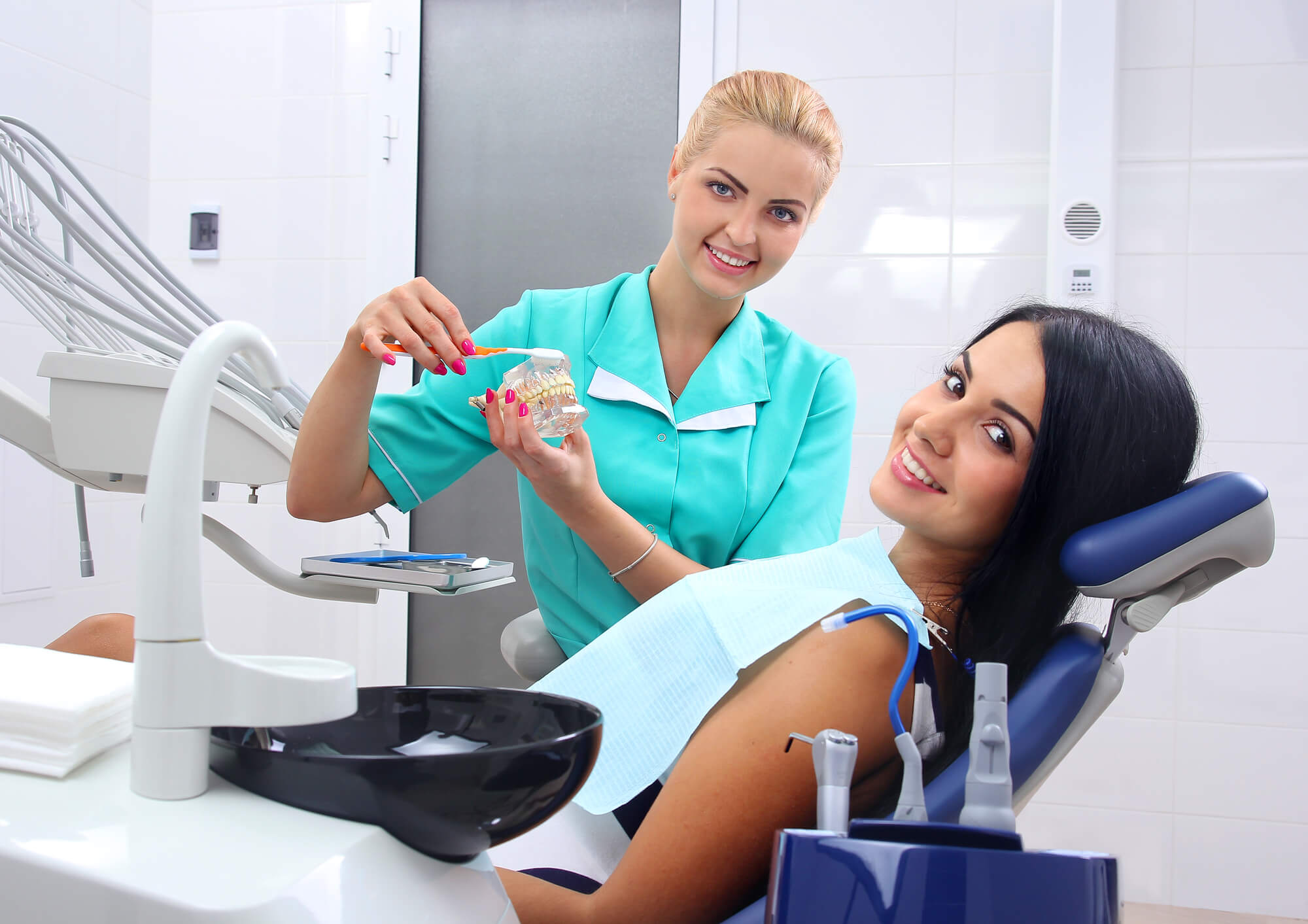 dental assistant and patient smiling at the camera