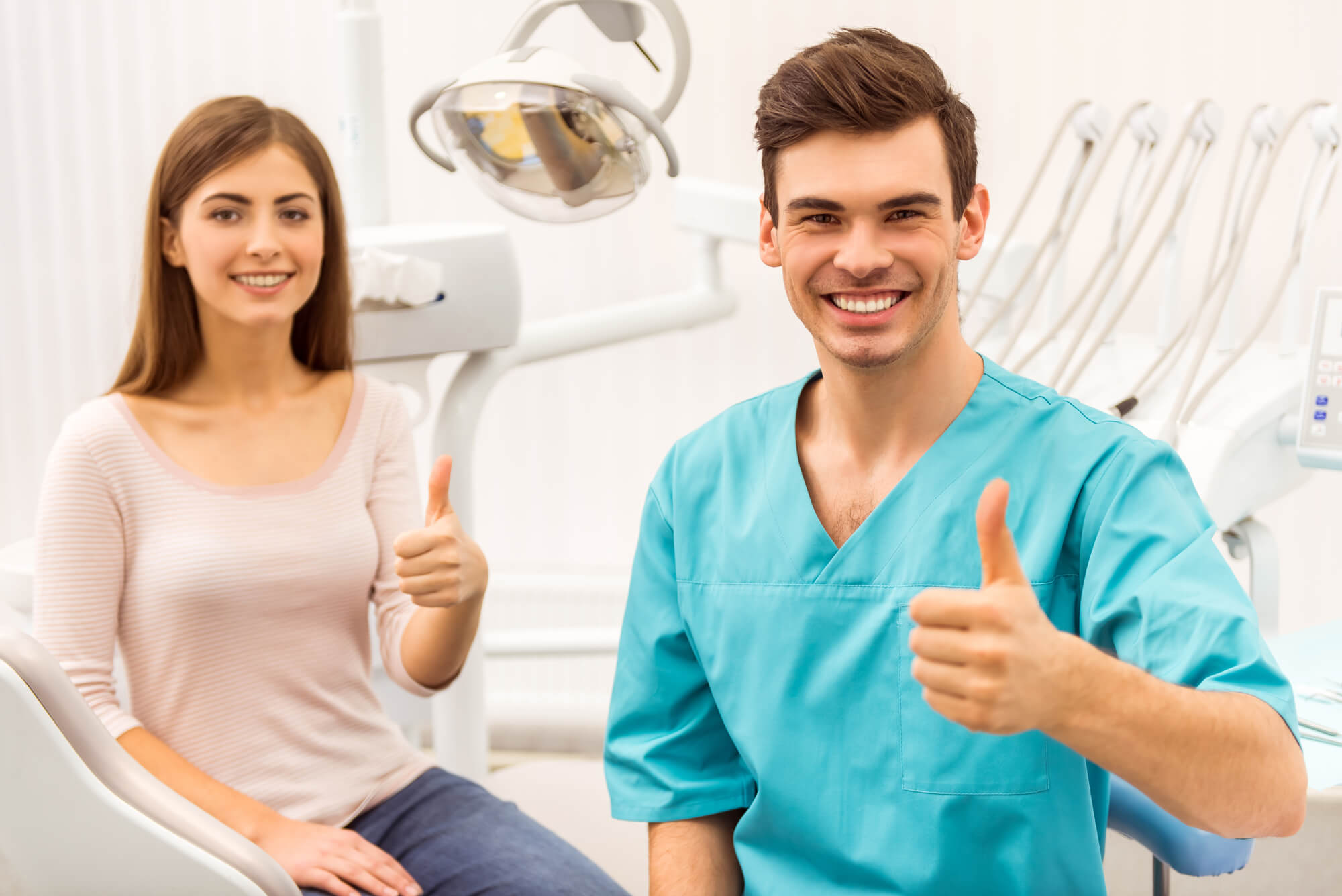 dentist and patient both smiling and giving thumbs up