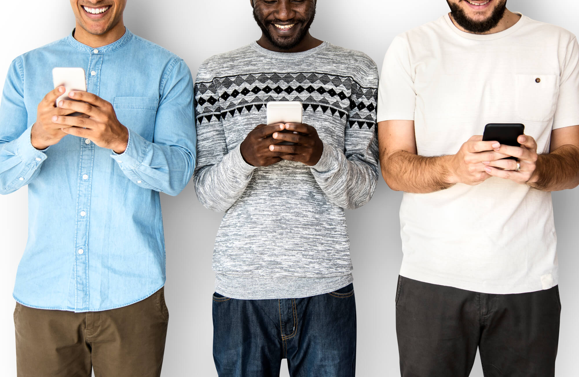 three men smiling while using their smartphones