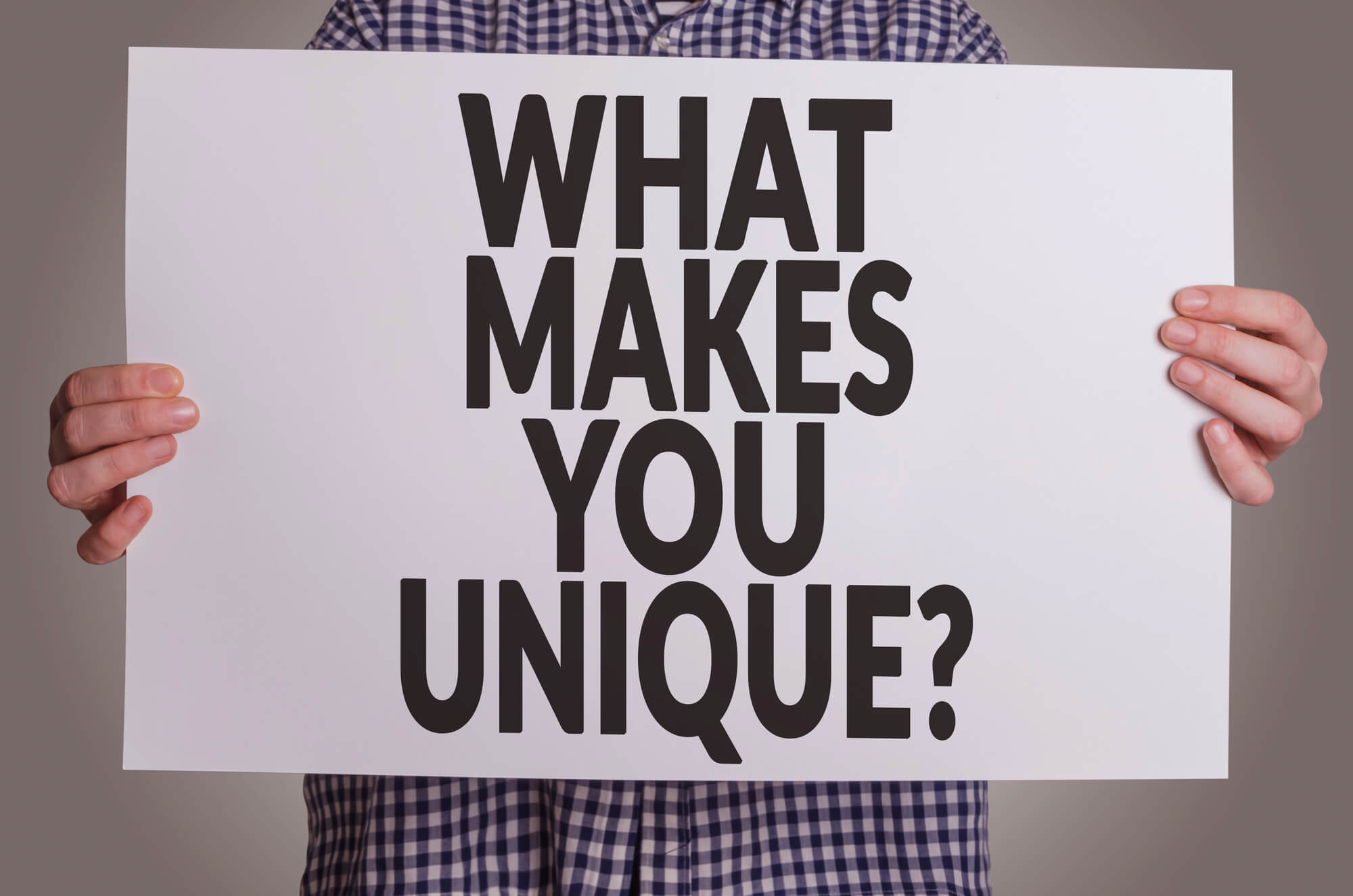 man holding sign that says what makes you unique