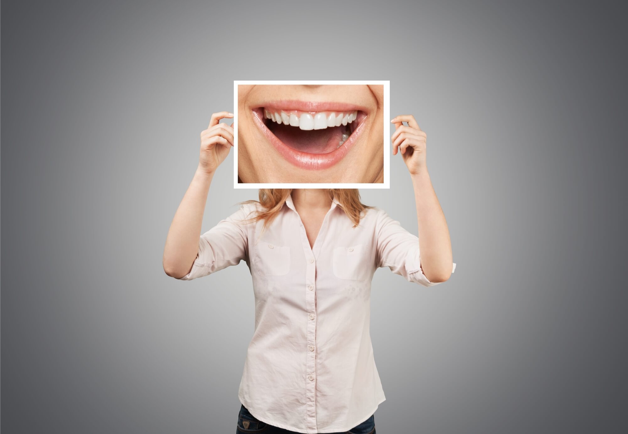 patient covering face with a photo of her big smile