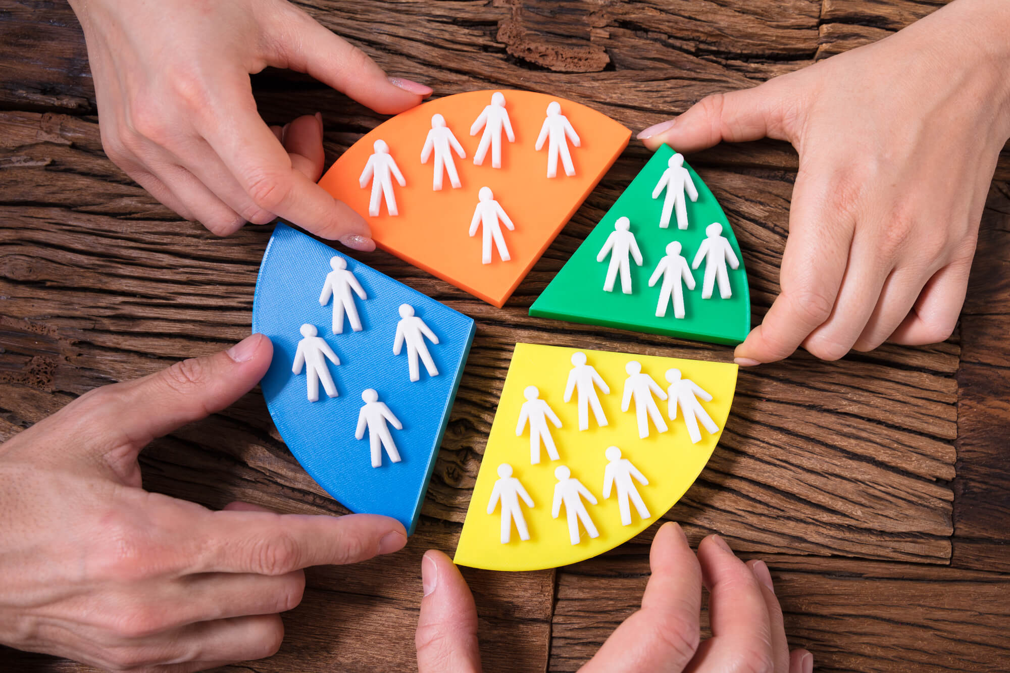 marketers holding pieces of pie chart with groups of people on each