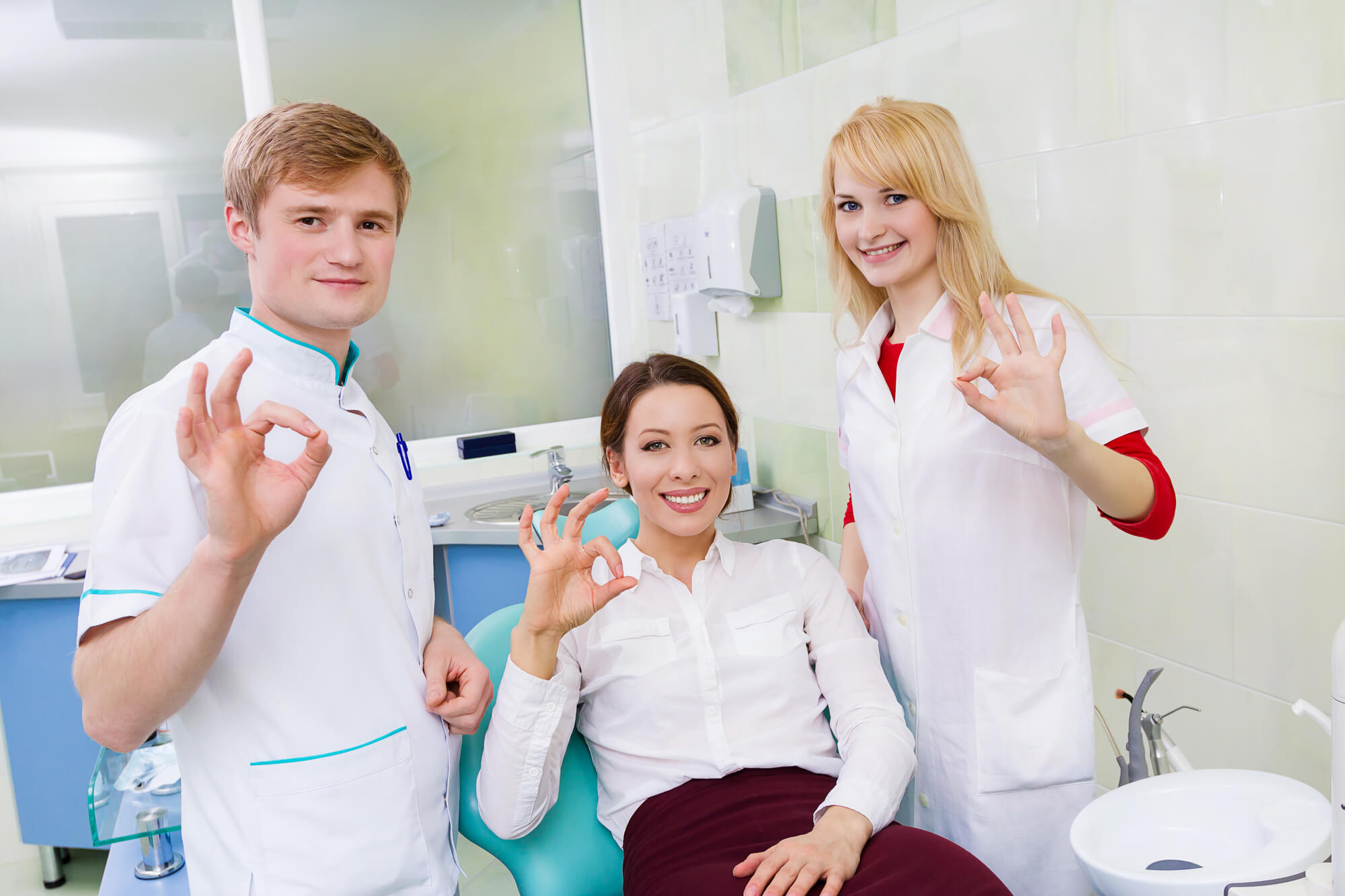 dentist and dental assistant posing with happy patient