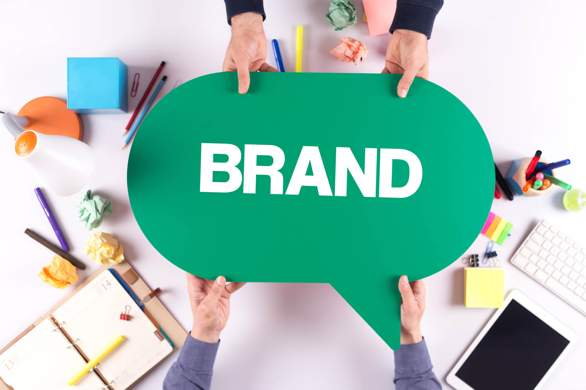 two-persons-holding-speech-bubble-with-word-brand