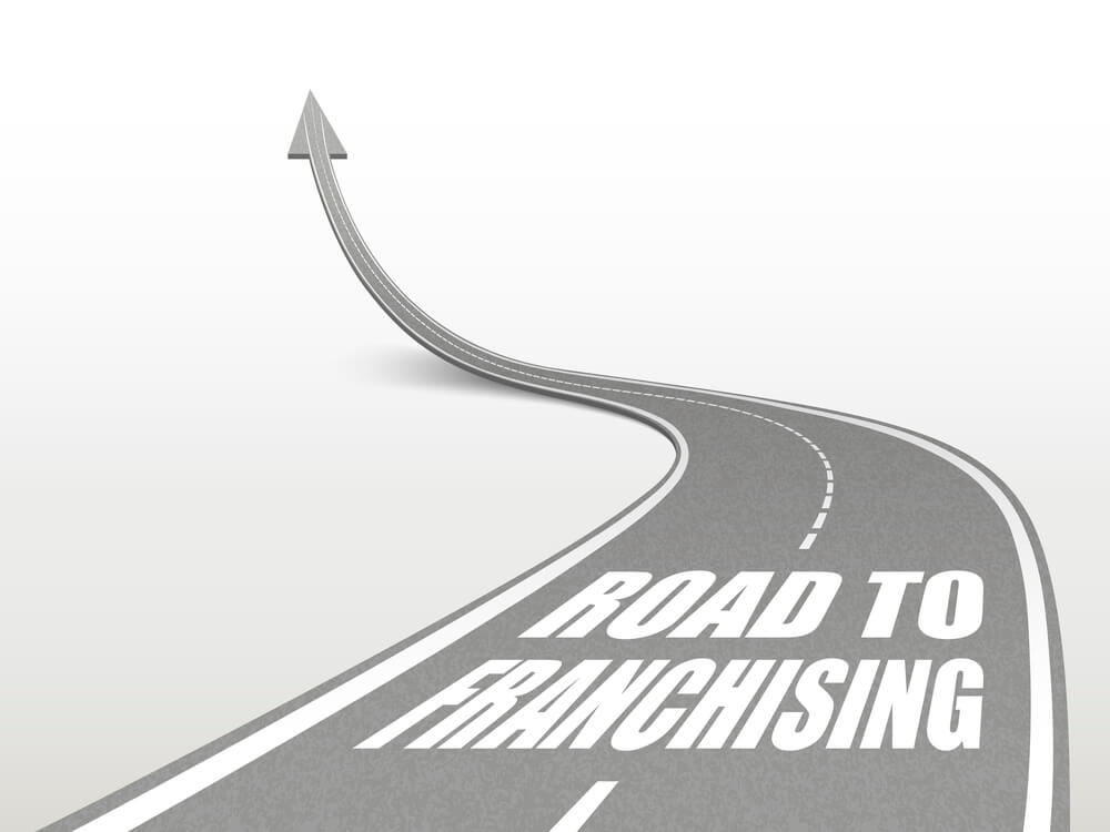 Illustration of a road pointing upward that says "road to franchising".