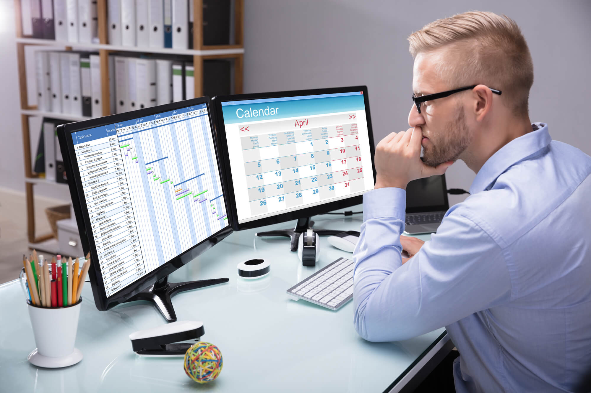young man organizing schedule on two monitor screens