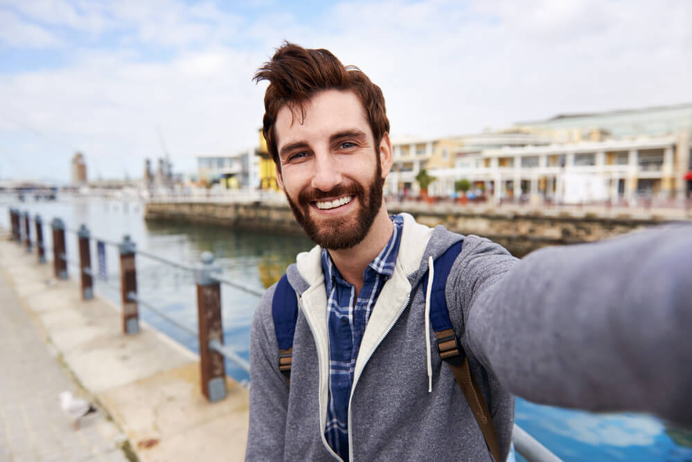 Backpacker and business owner sharing selfie on social media.