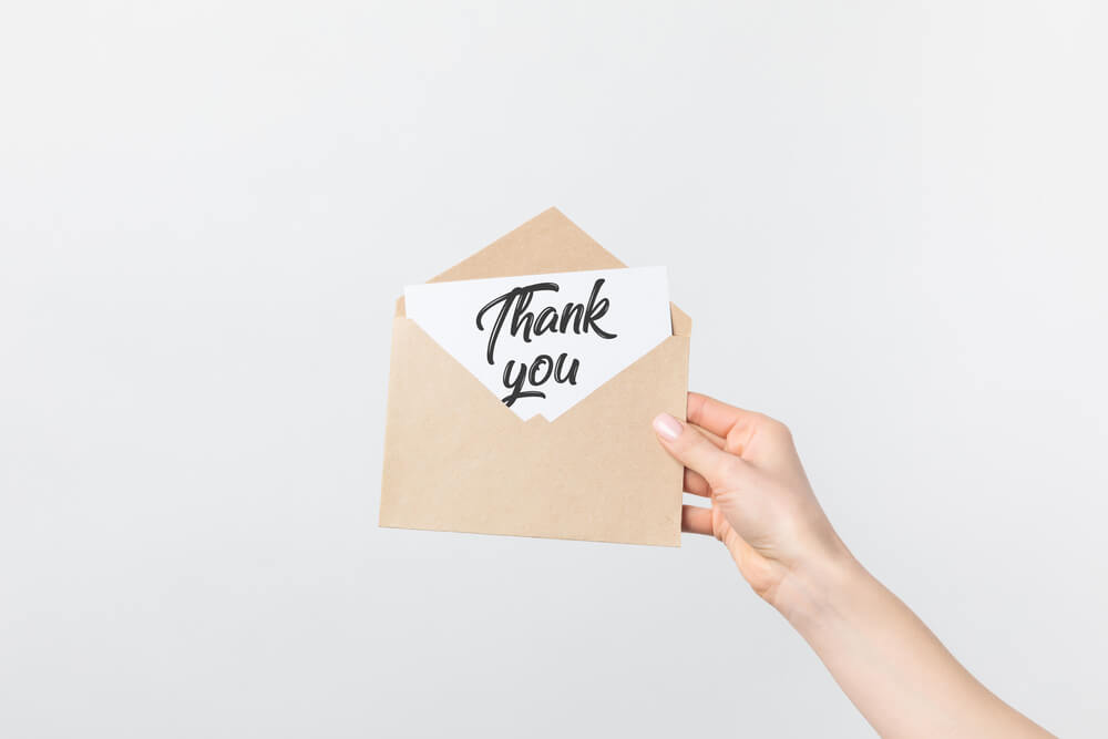 The words "Thank You" written on a paper inside an envelope