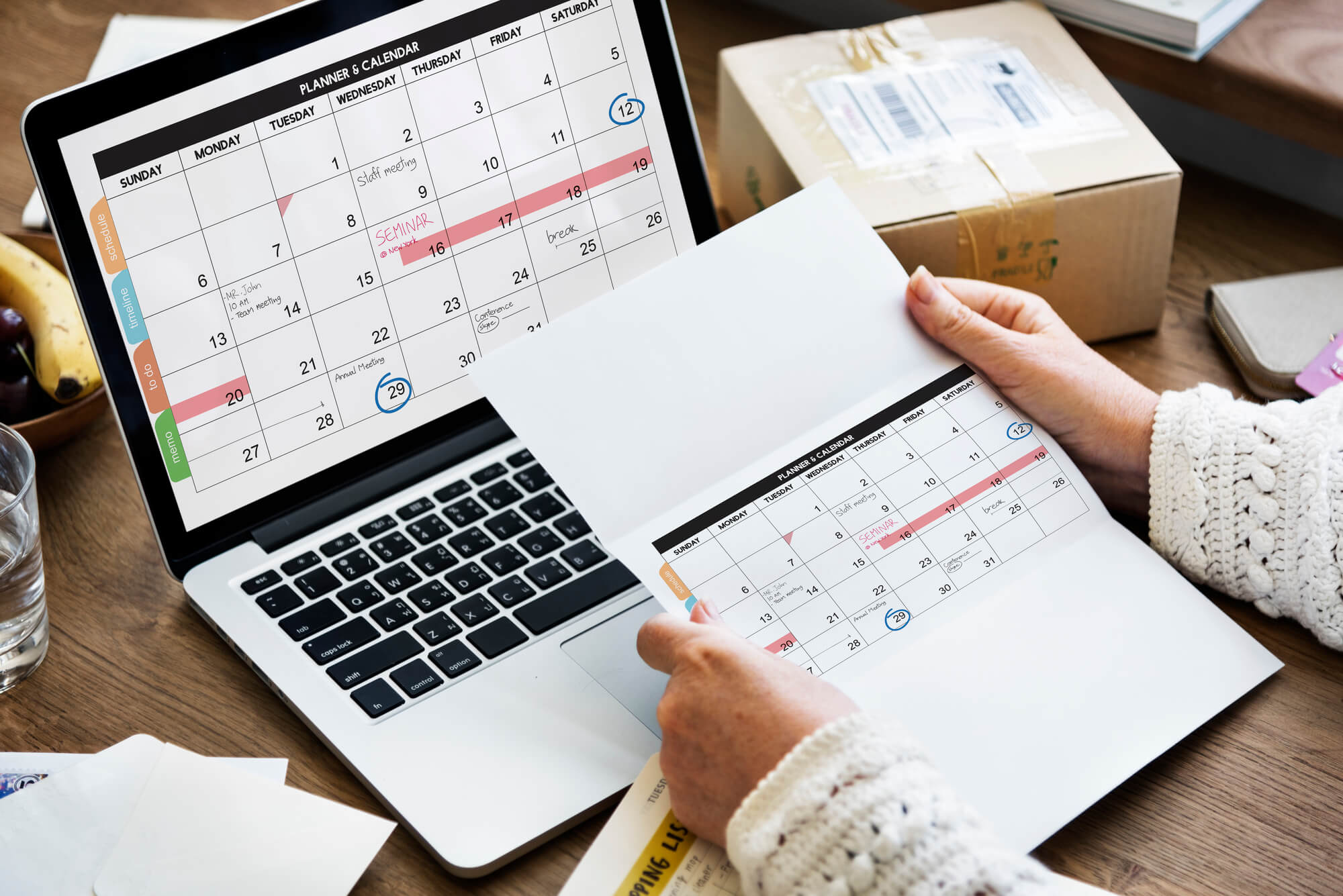 man holding a paper planner and transferring it to laptop