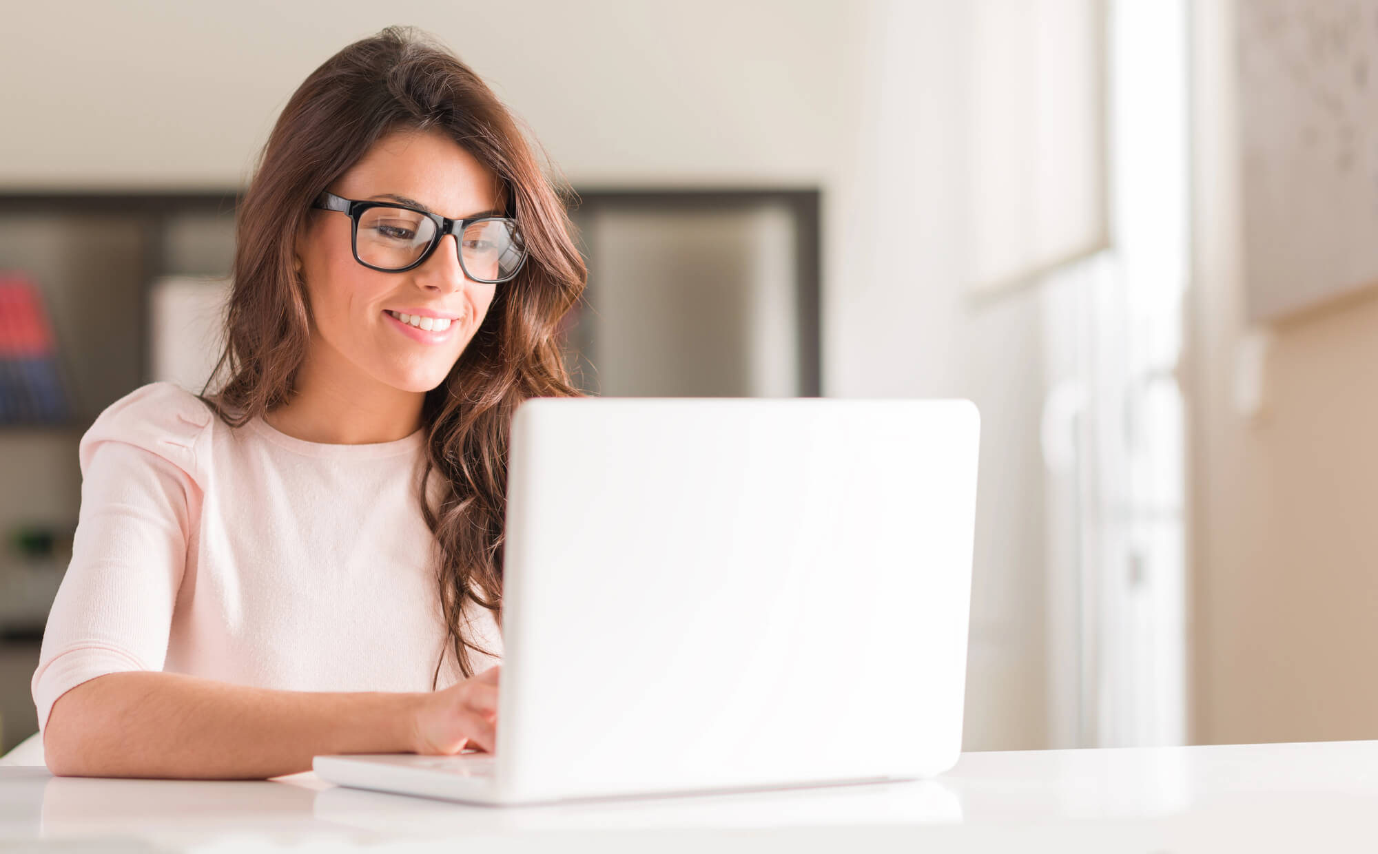 female professional smiling as she works on her laptop