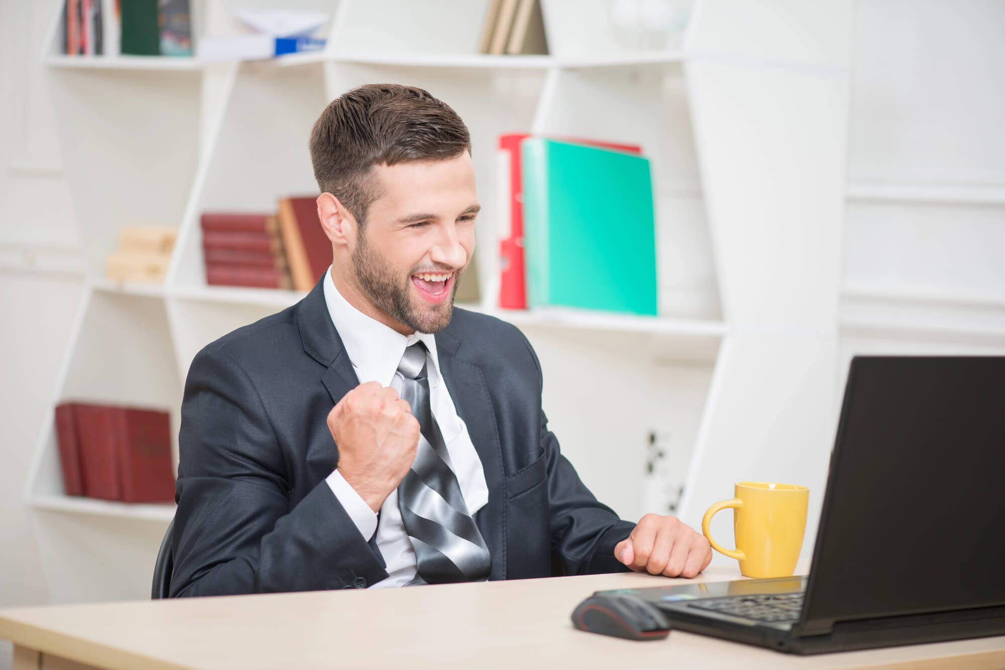businessman looking at his computer with a victorious pose