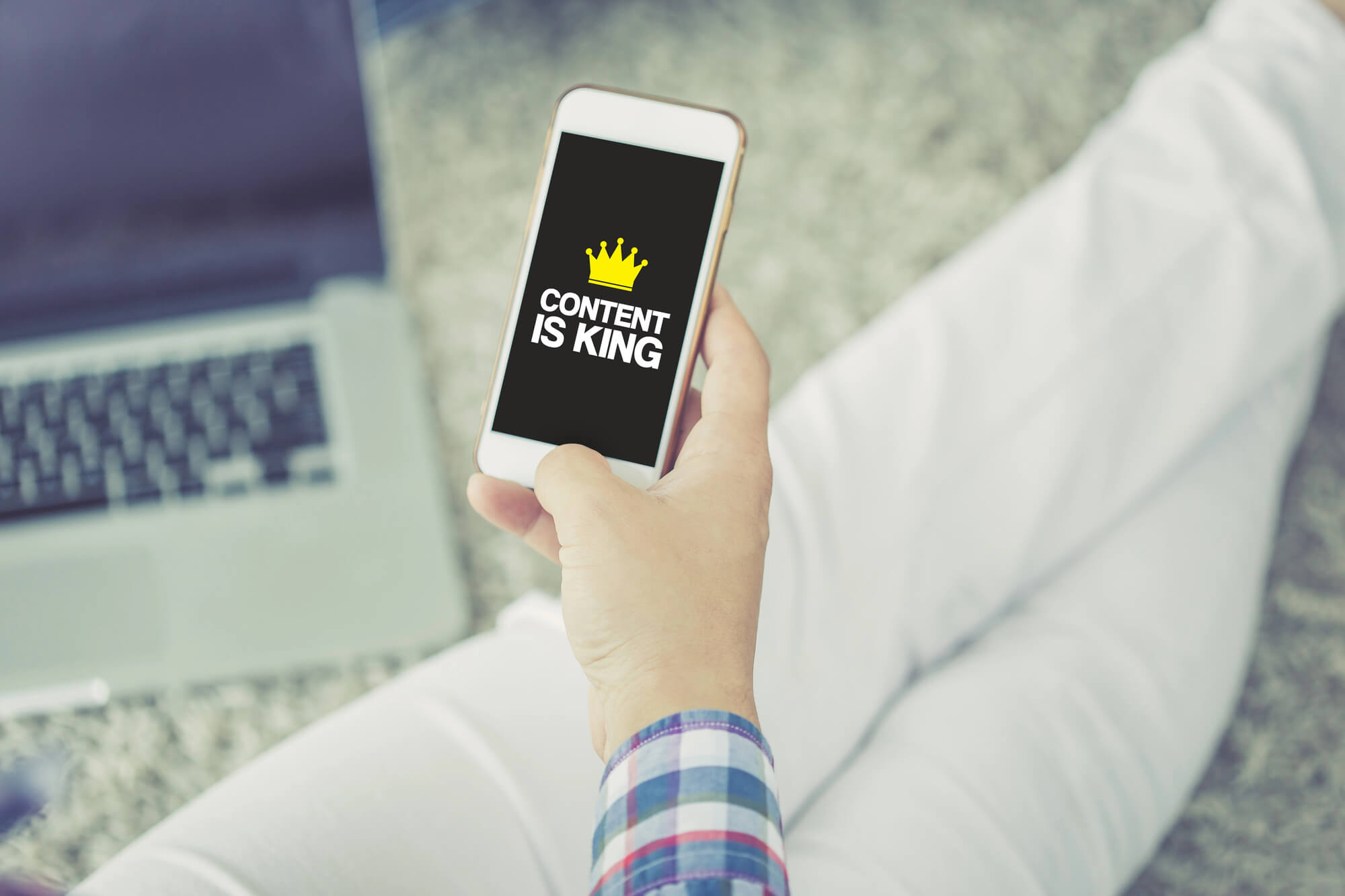 hand holding phone displaying content is king on screen