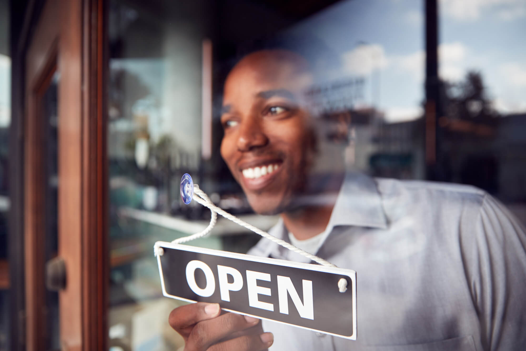 franchise owner placing an open sign on his shop