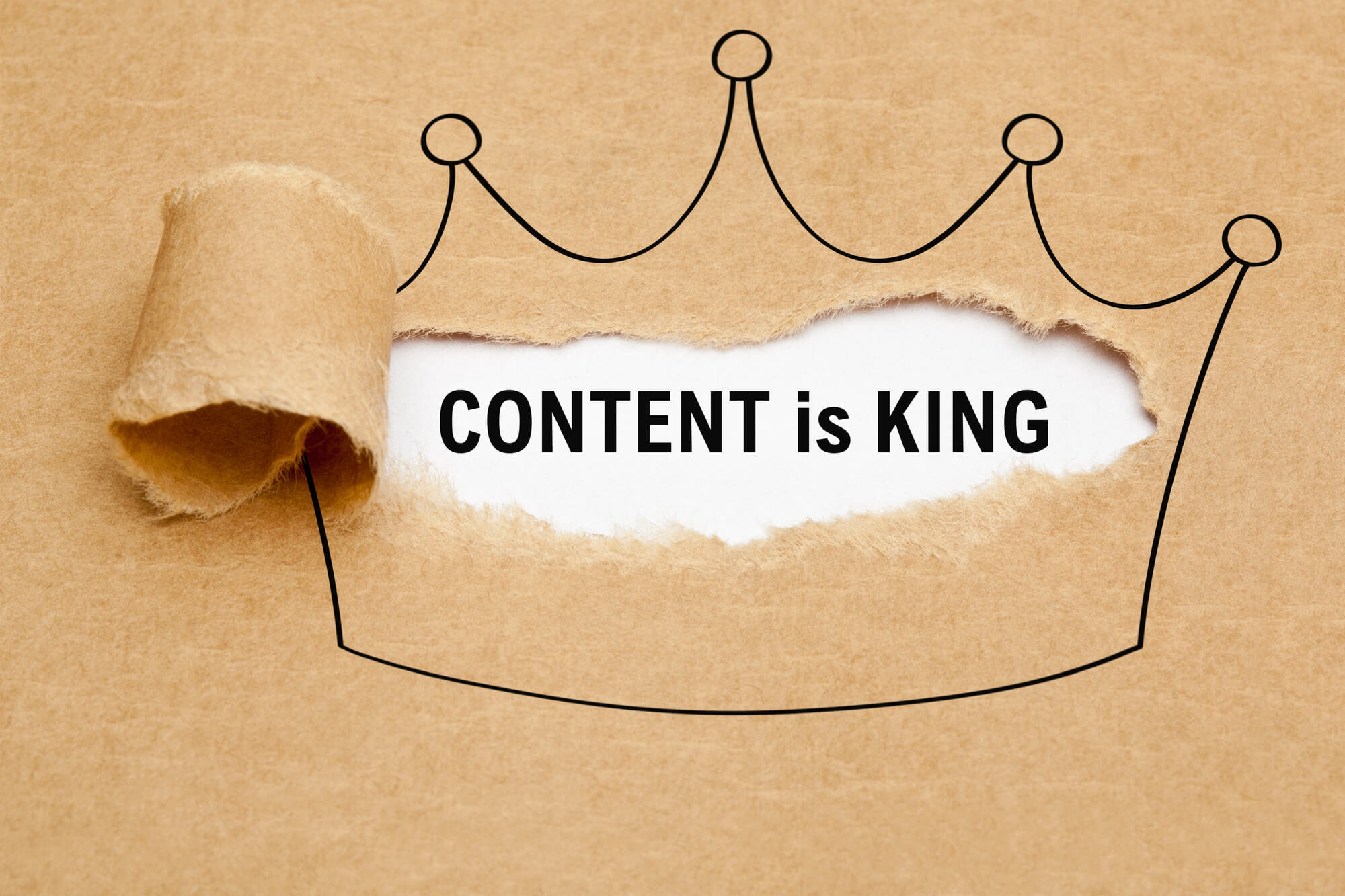torn paper revealing the phrase 'Content is King' inside a drawn crown