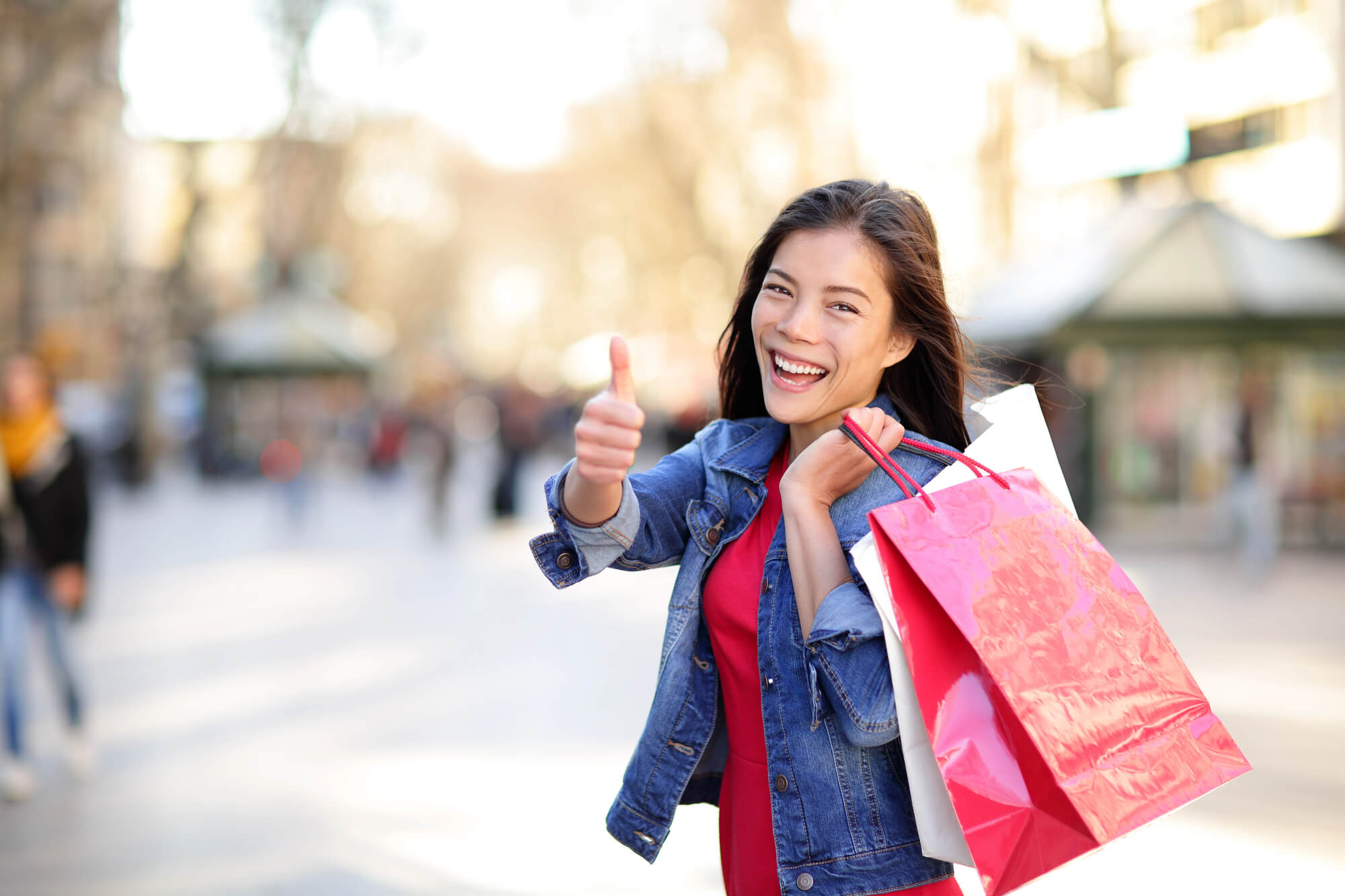 happy shopper posing with thumbs up while holding shopping bags