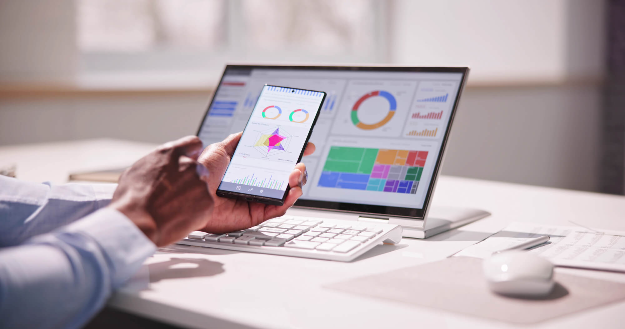 professional man analyzing metrics on phone and desktop