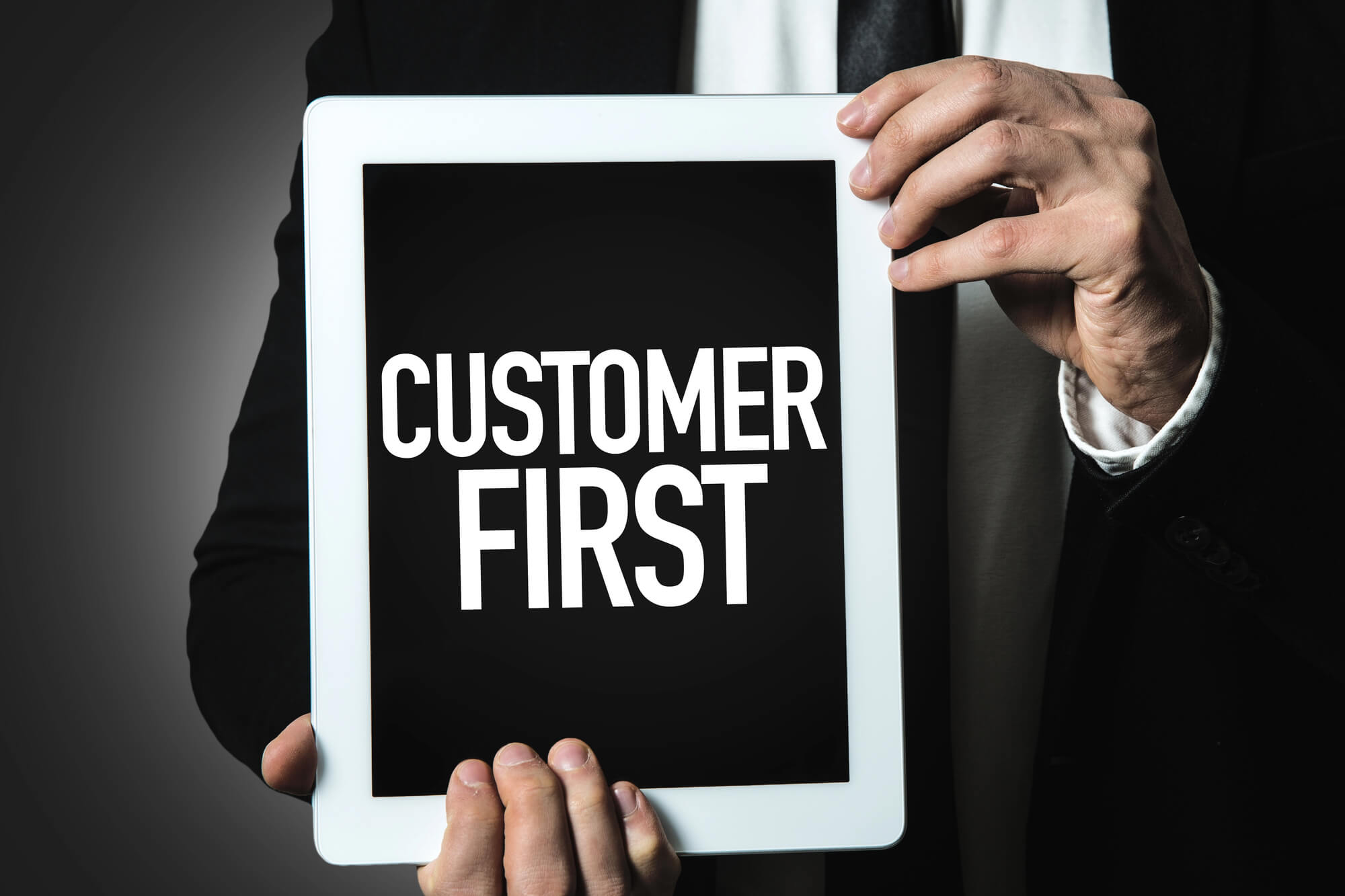 businessman holding tablet with 'customer first' on screen