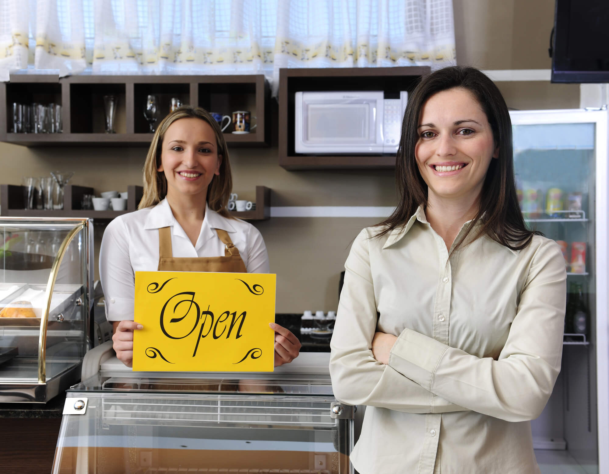 proud cafe owner and staff member behind her holding an open sign