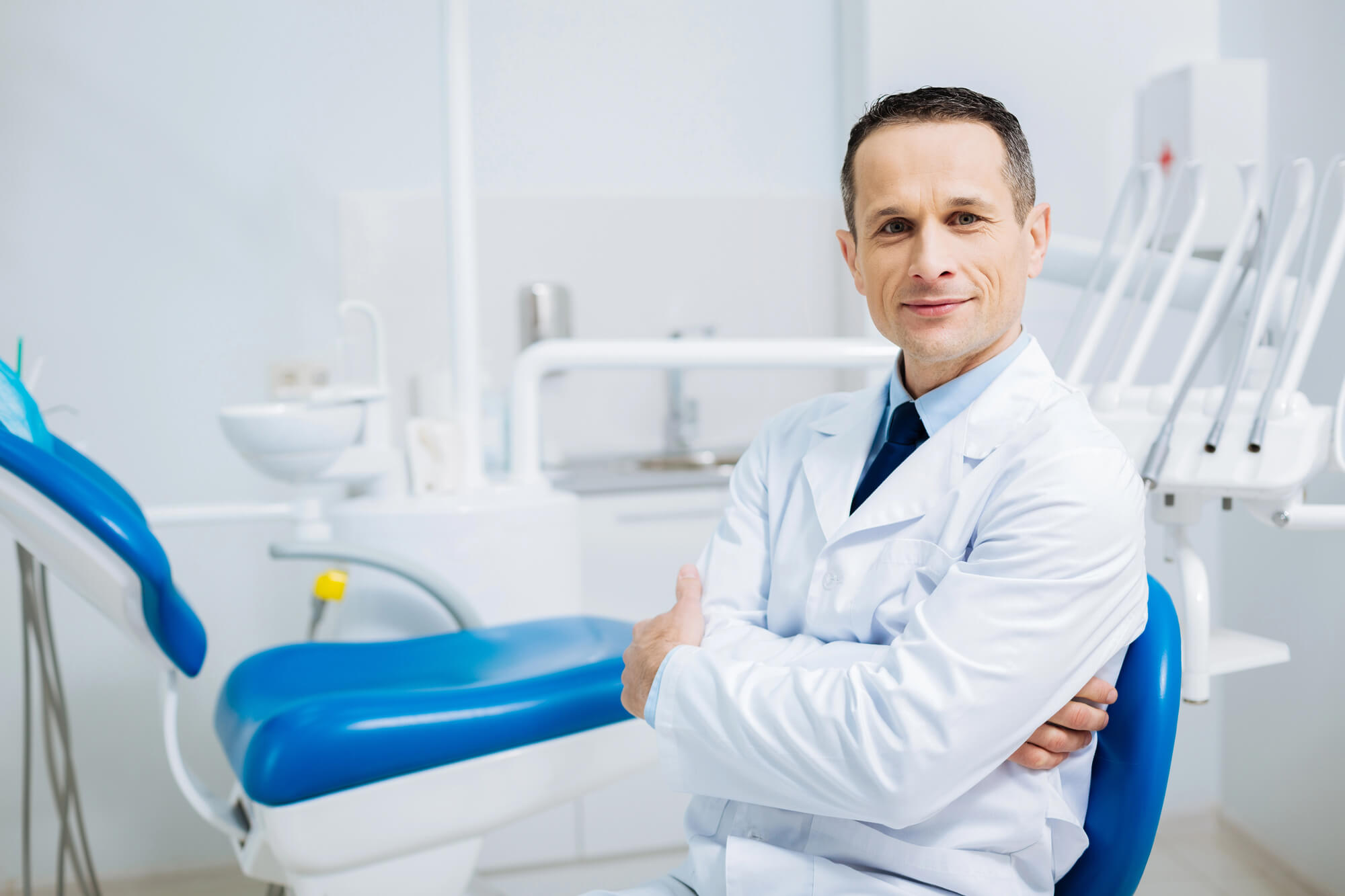 dentist looking pleased while sitting down on his clinic