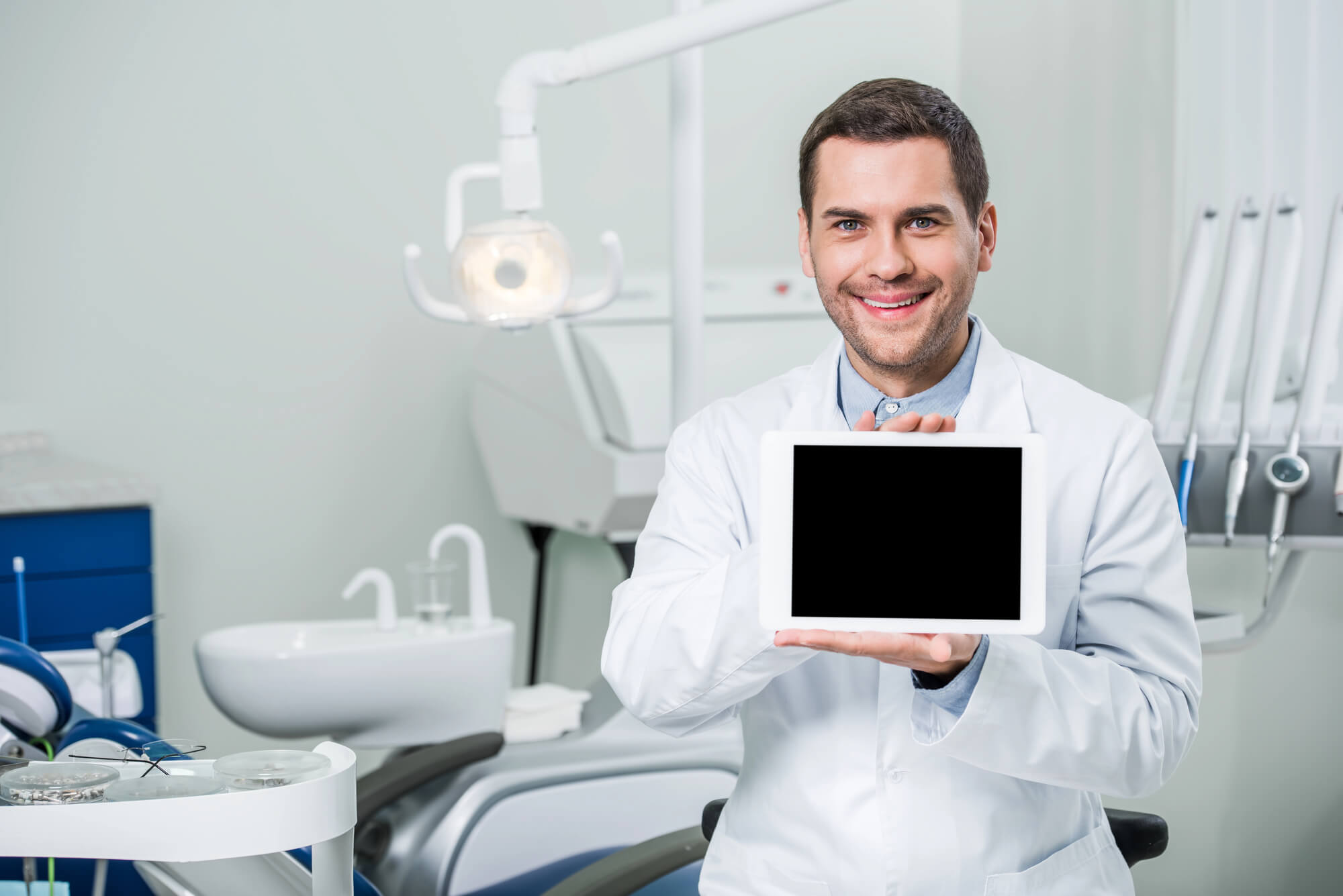 cheerful dentist showing a tablet with blank screen