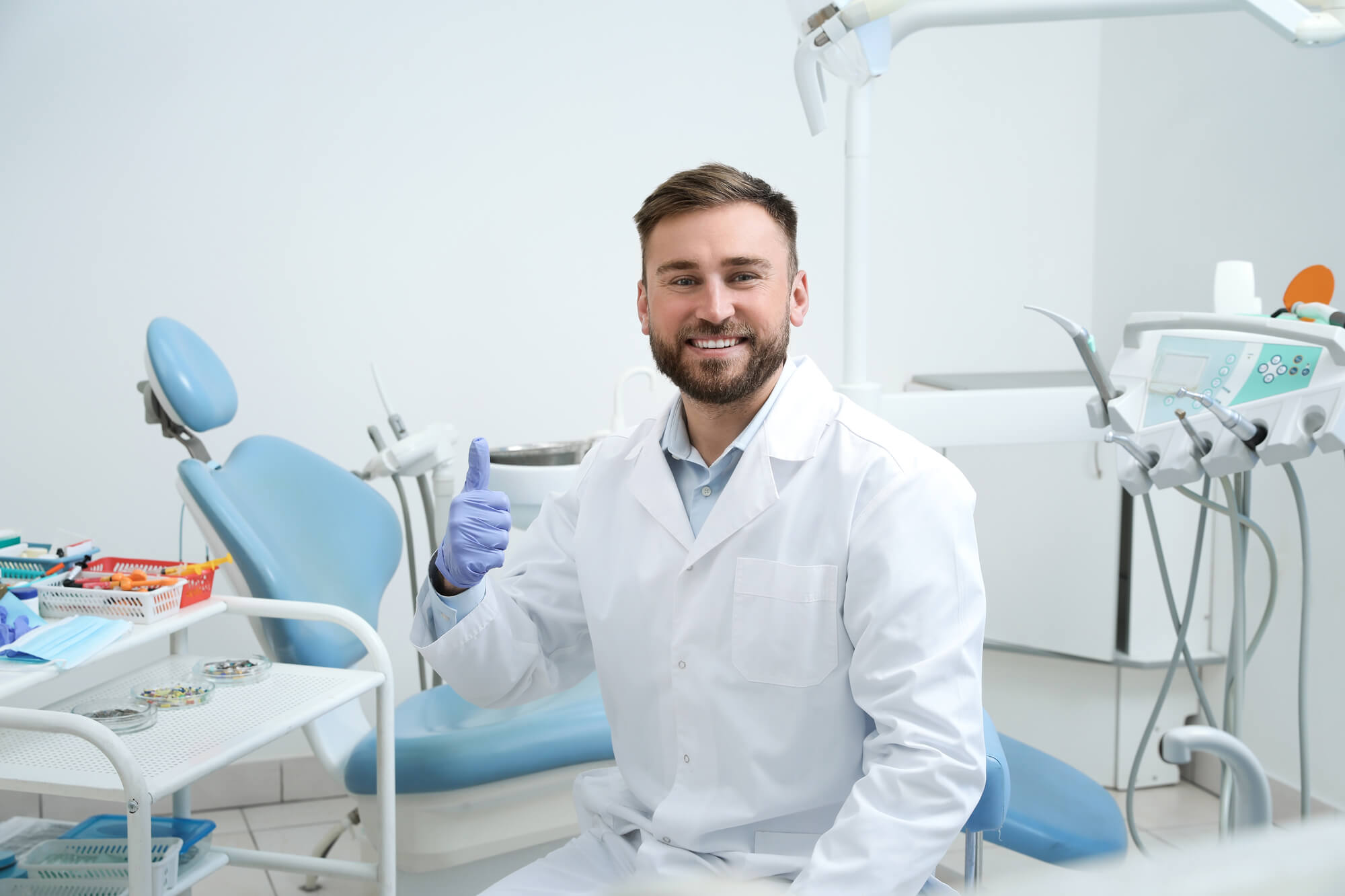 smiling male dentist holding a thumbs up
