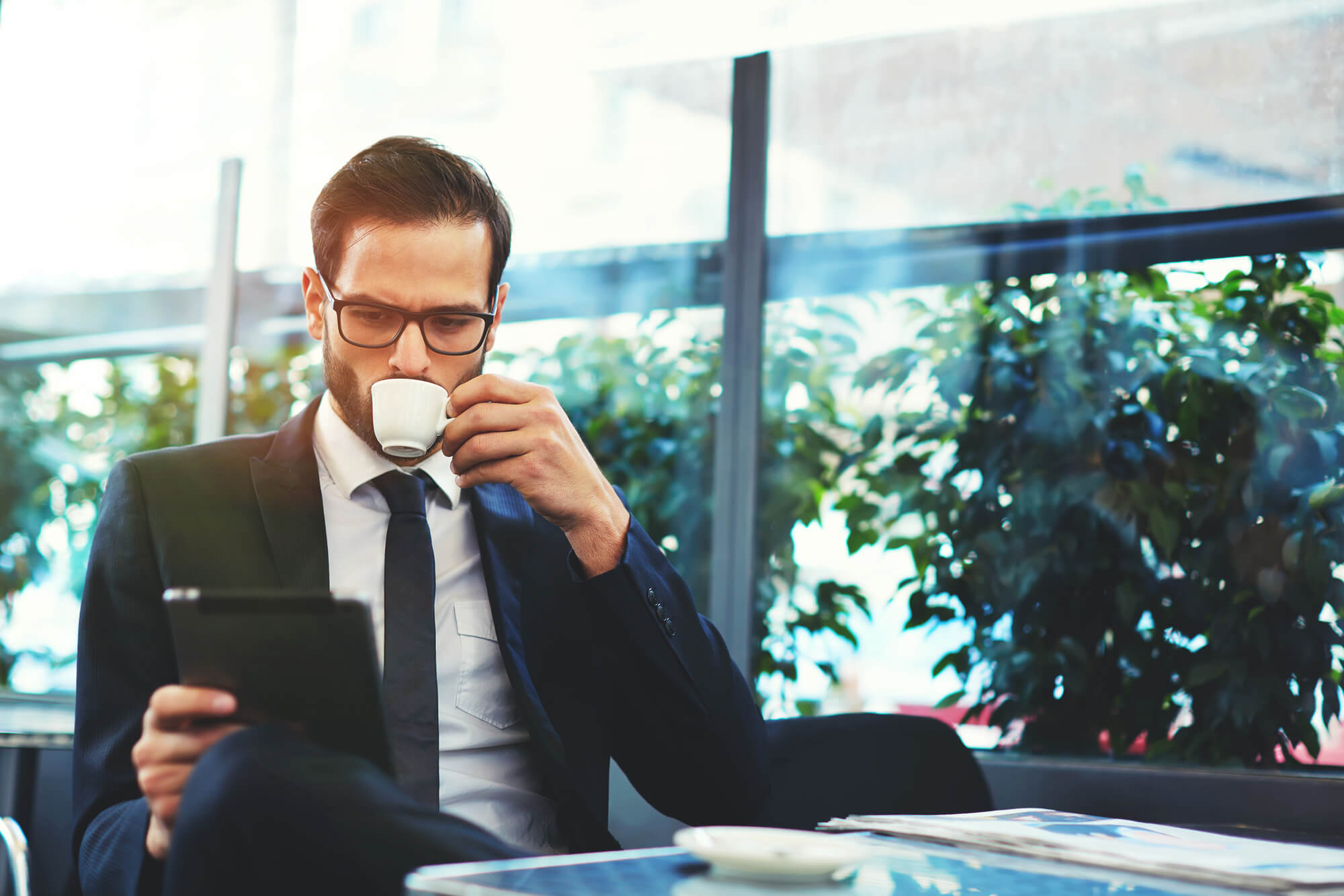 businessman looking at tablet while sipping coffee local seo