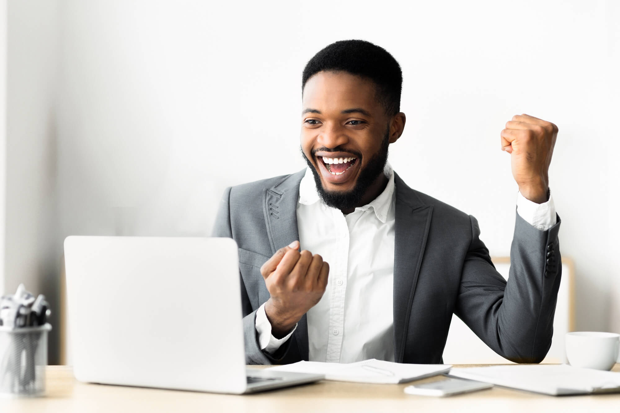 Excited businessman celebrating while watching something on his laptop