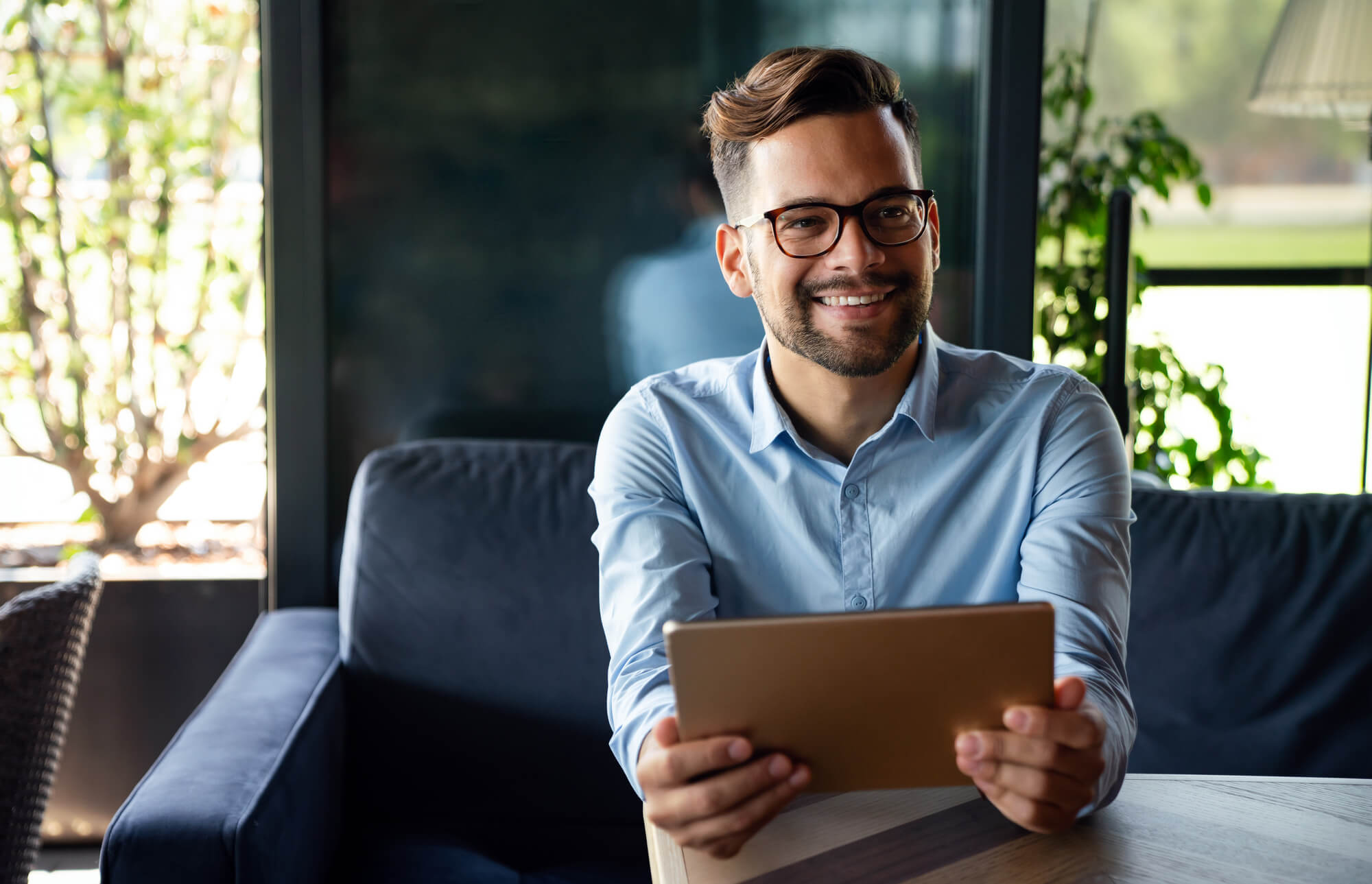 young entrepreneur smiling as he holds a tablet