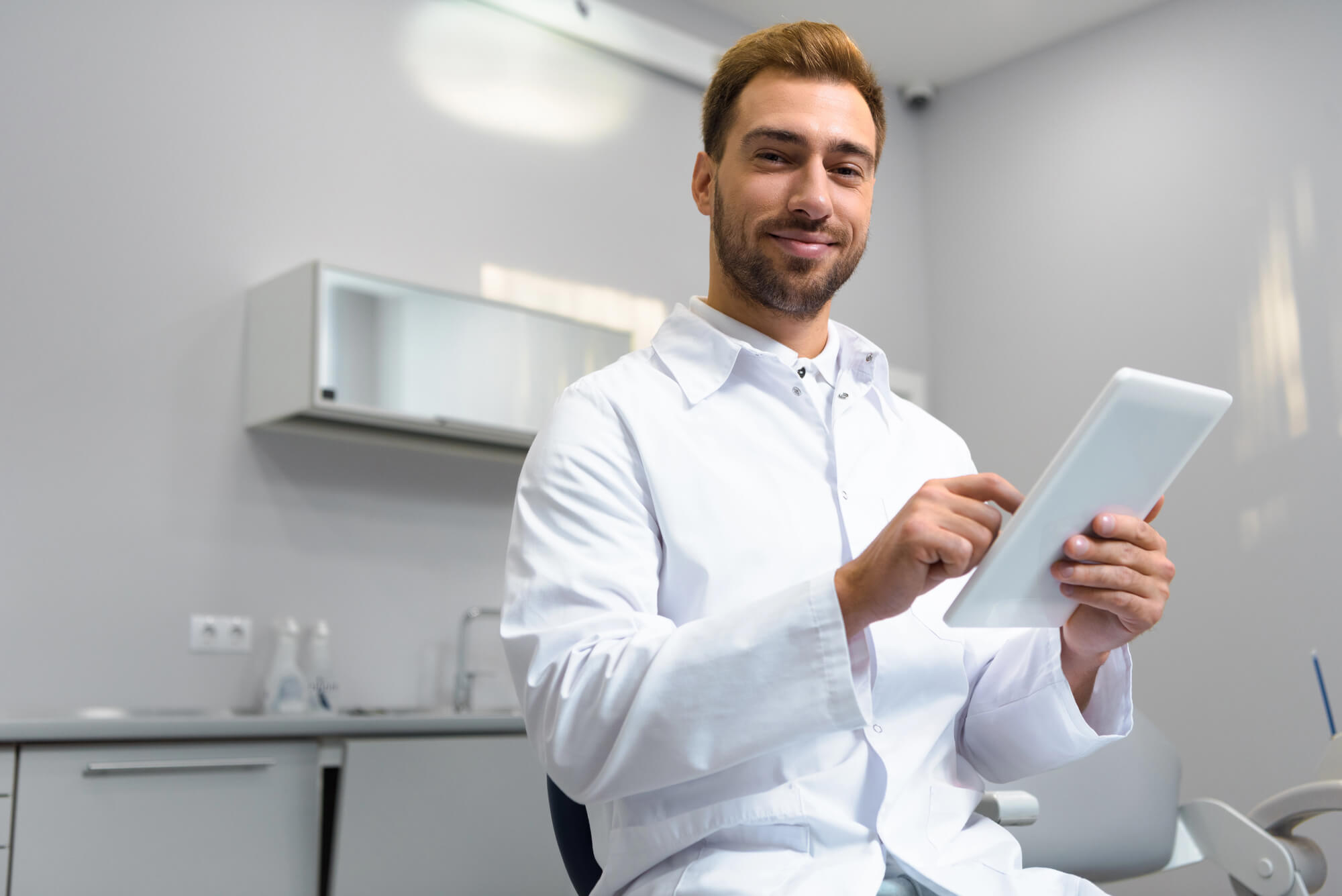 dentist looking pleased as he uses a tablet