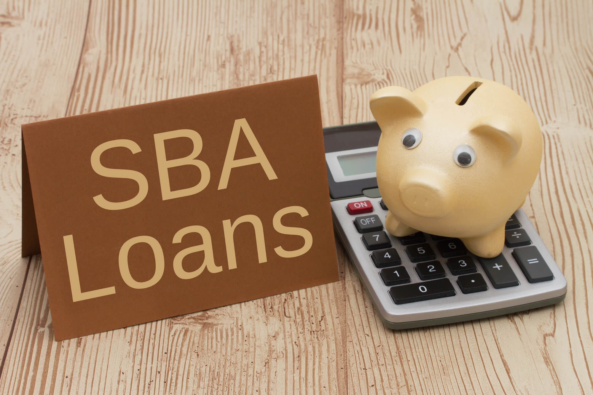 card showing sba loans with piggy bank and calculator beside it 