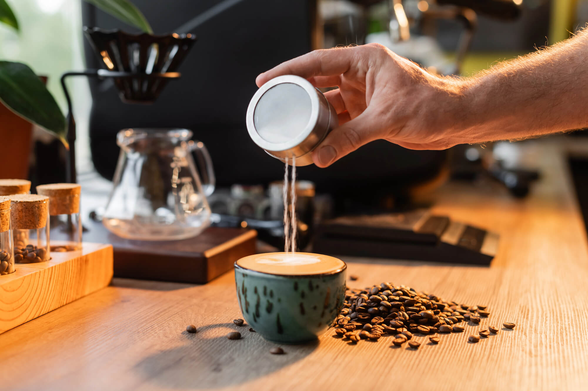 cropped image of barista pouring sugar into a cup of coffee