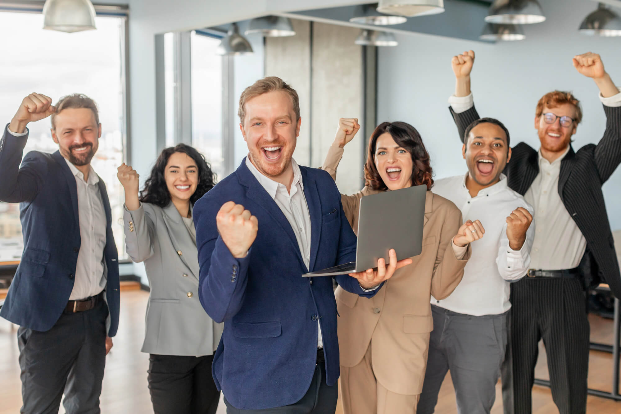 cheerful business team celebrating a big success in a bright office, with team members smiling, raising fists in excitement, and radiating positivity and teamwork