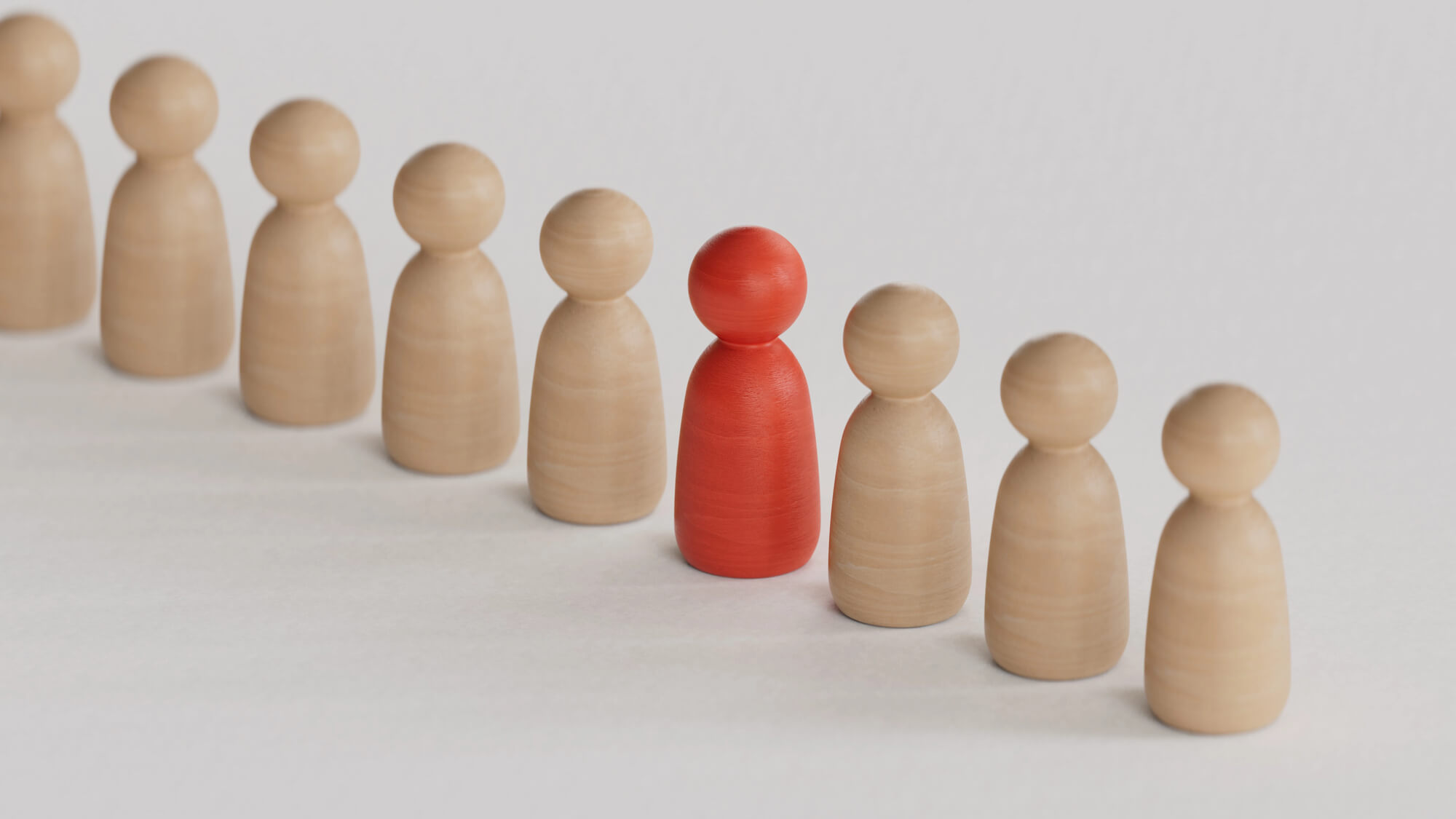 a row of wooden figures with one red figure standing out in the center