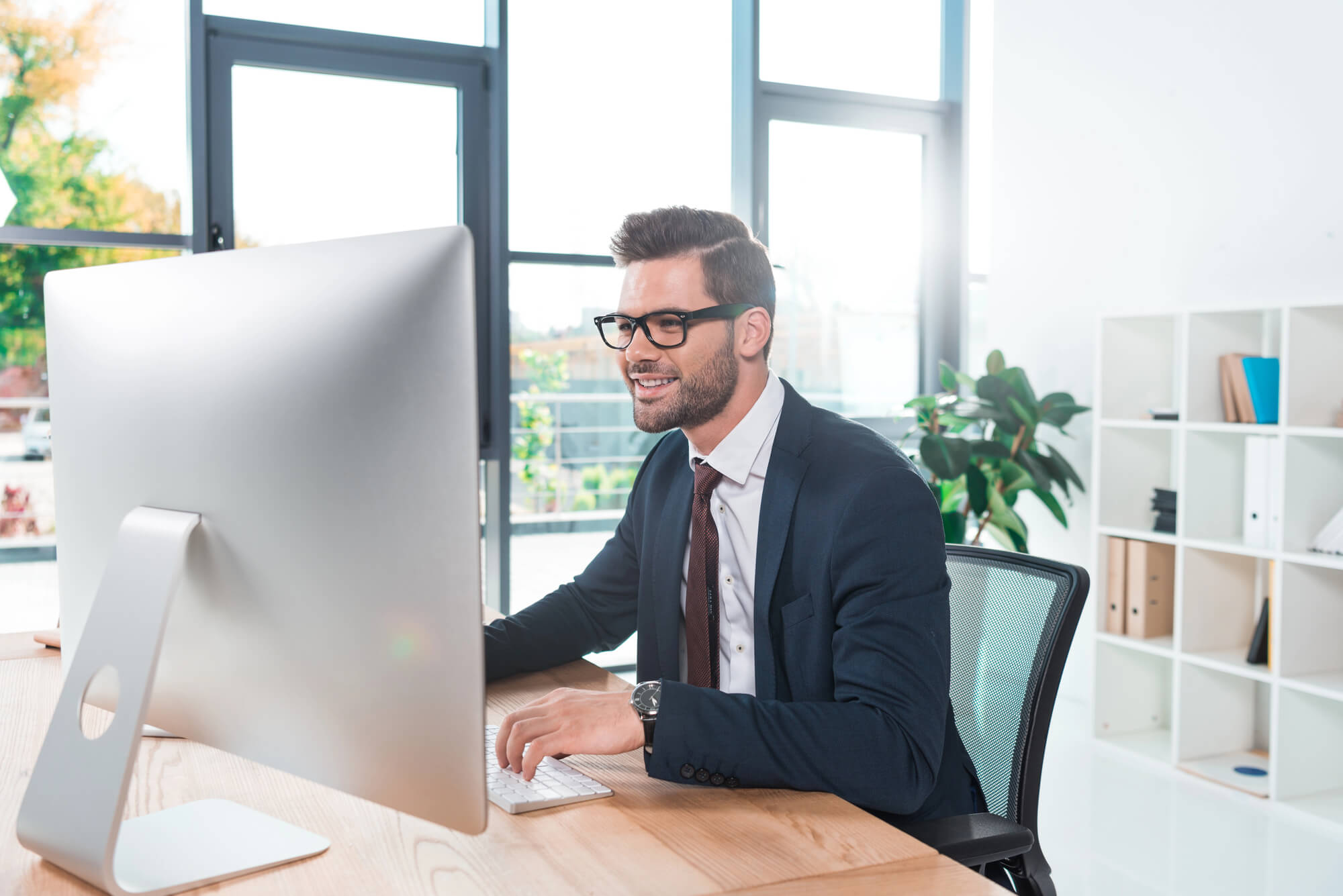 an entrepreneur smiling as he works on his computer in a modern office