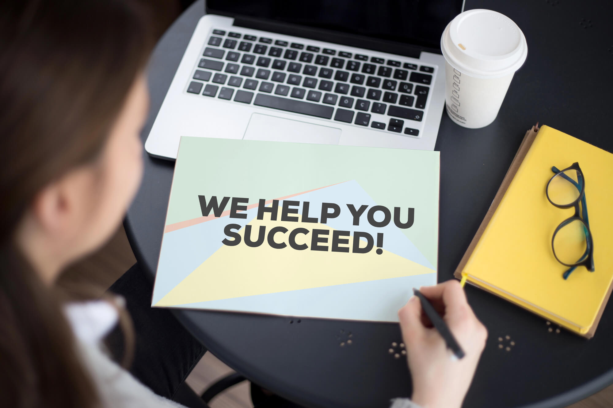 woman holding a pen, looking at a document that says "WE HELP YOU SUCCEED!"