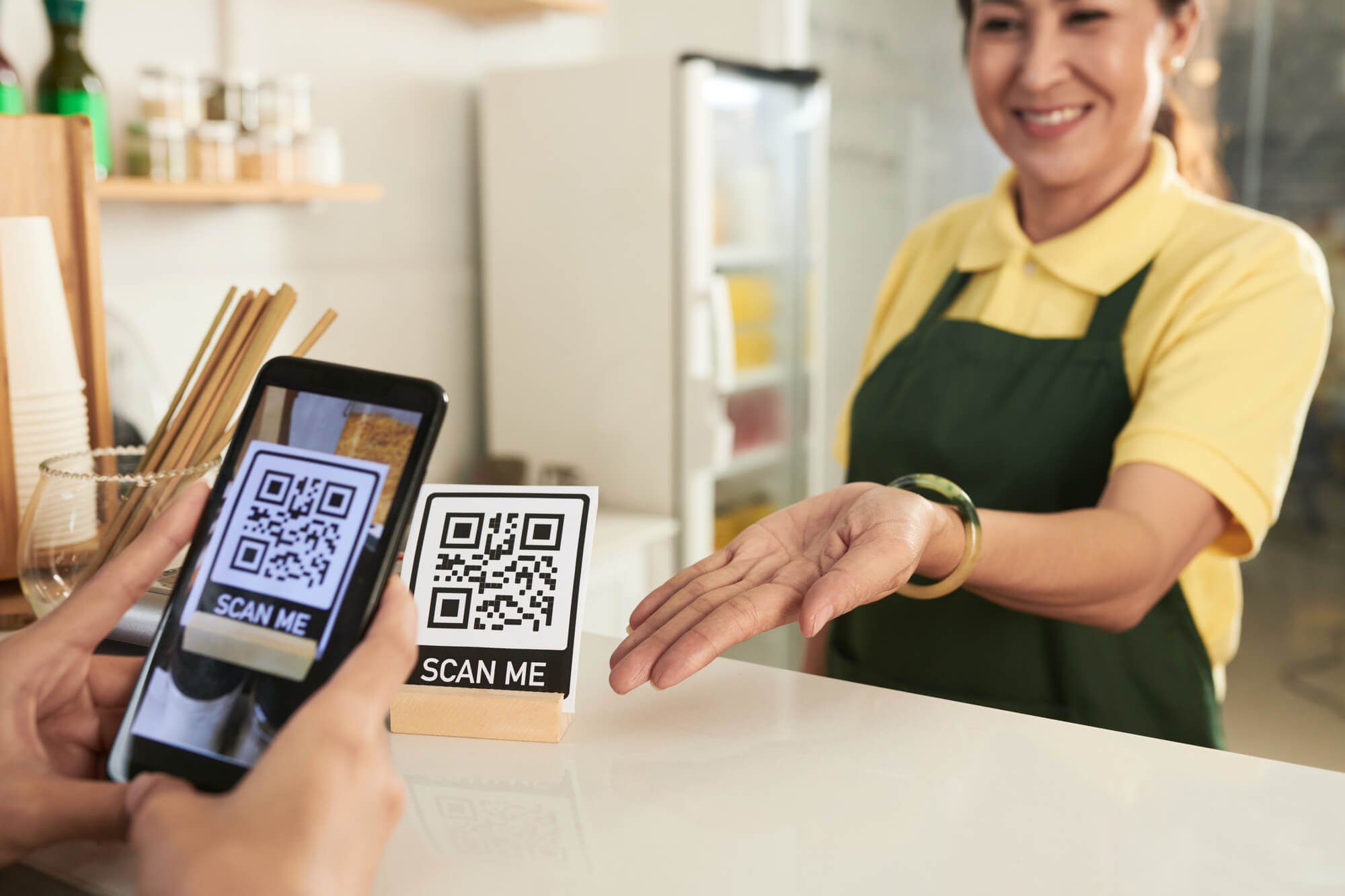a smiling business store owner directs customer to scan the QR code