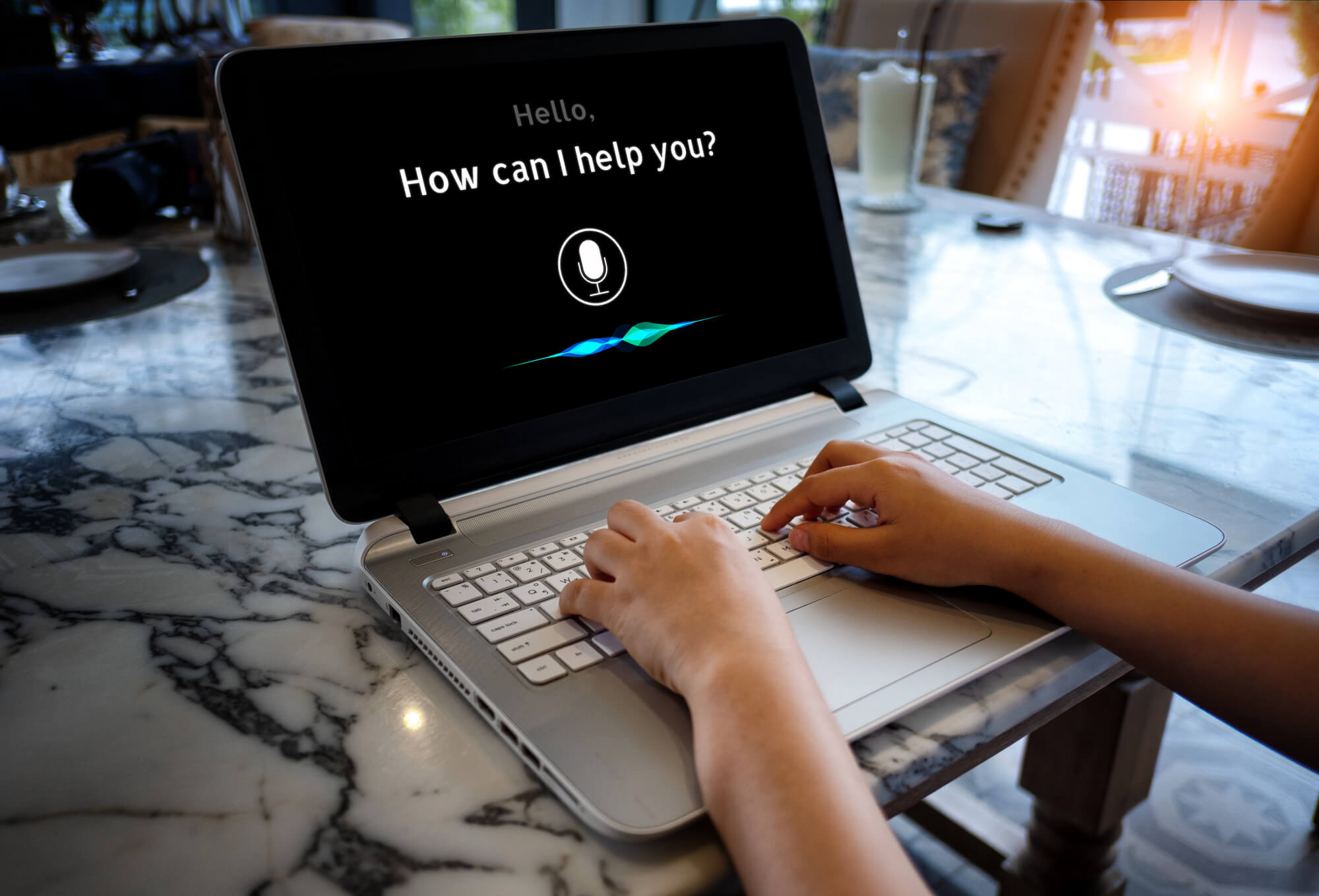 person using a laptop with a voice assistant screen displaying "How can I help you?" and a microphone icon