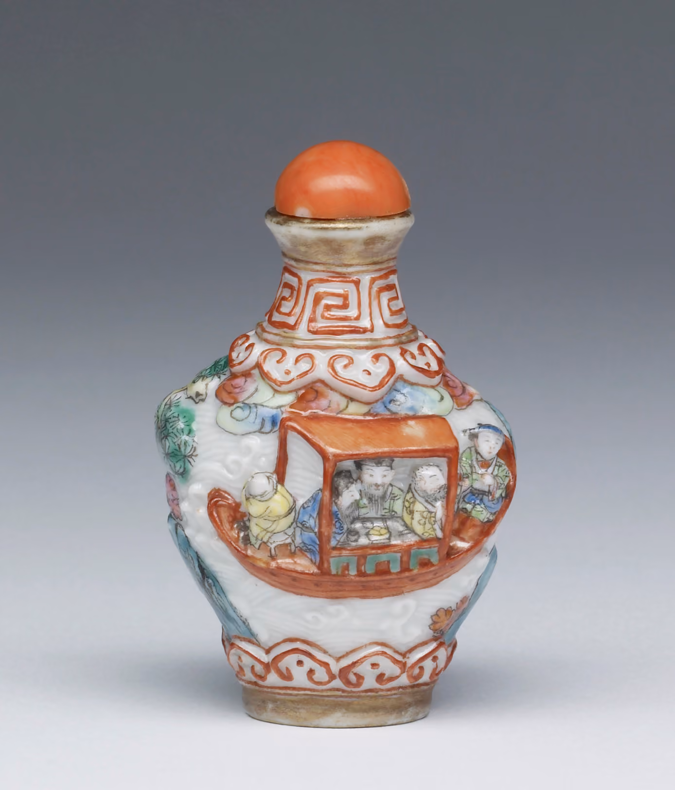 Enamelled porcelain modelled in high relief with figures in a landscape and a boat