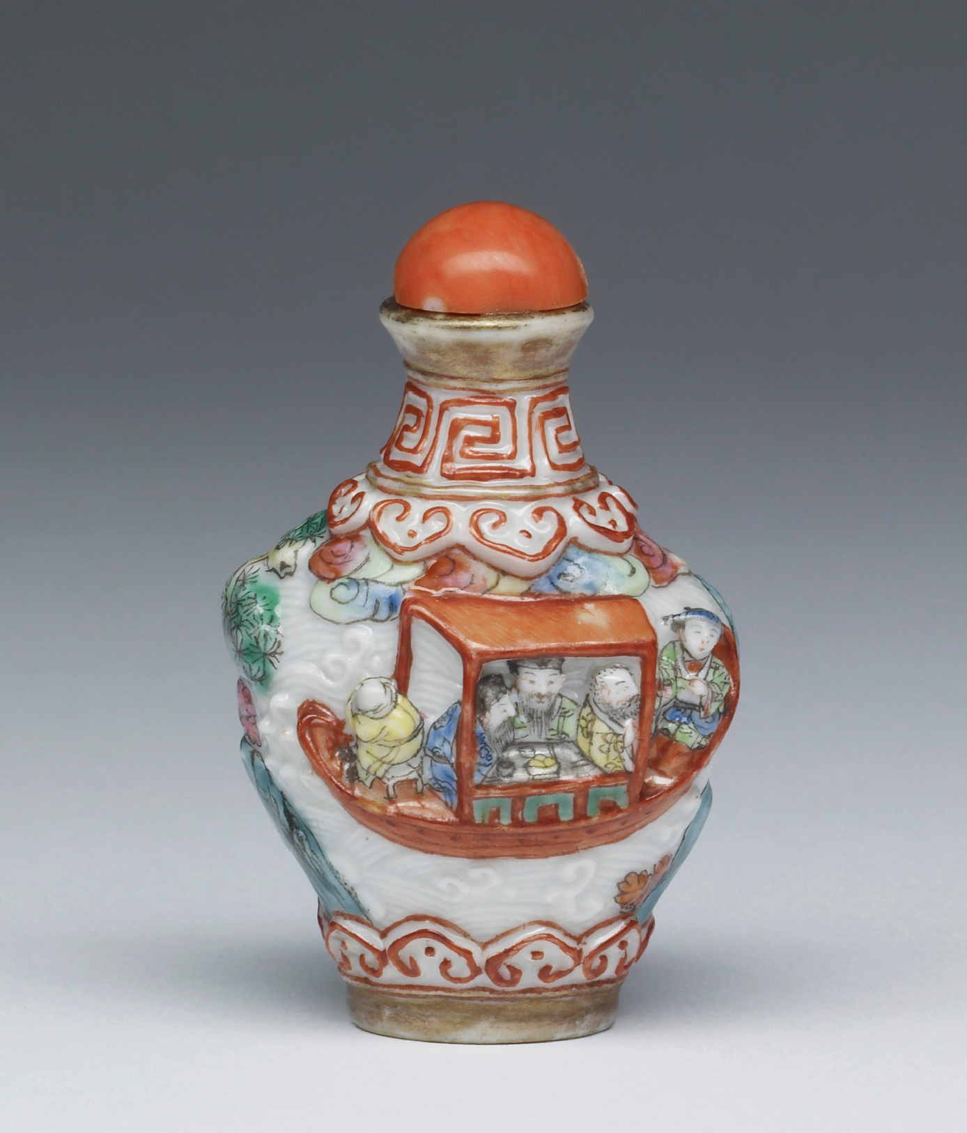 Enamelled porcelain modelled in high relief with figures in a landscape and a boat