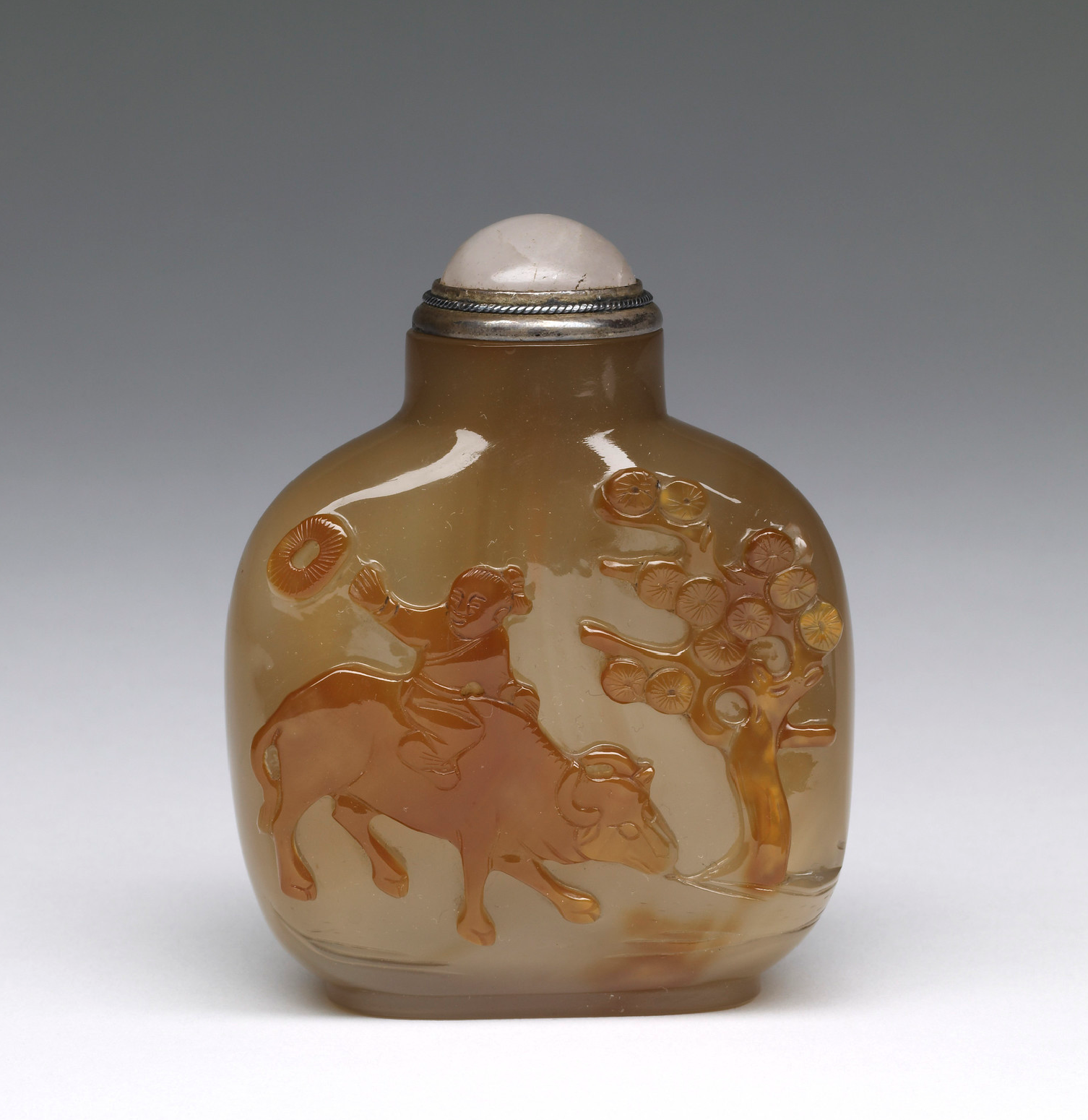 Agate carved with boy on a buffalo beside a pine tree