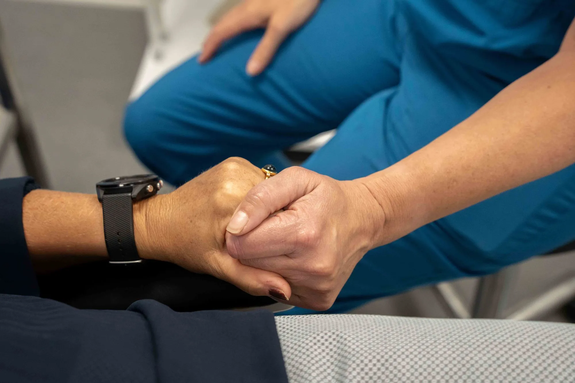 To personer holder hinandens hænder som tegn på støtte og omsorg.