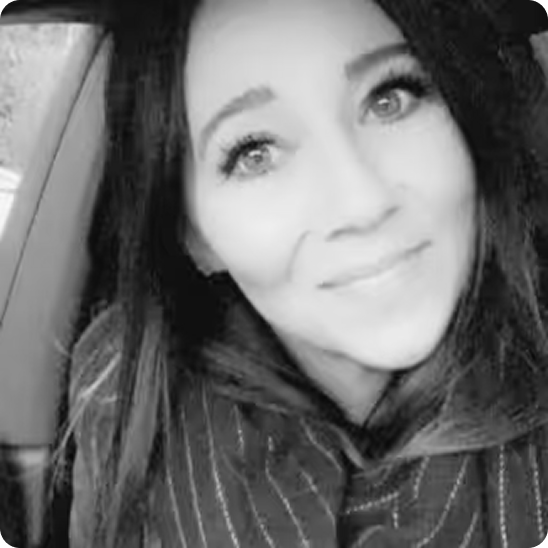 Black and white photo of a woman with long hair smiling gently inside a car.