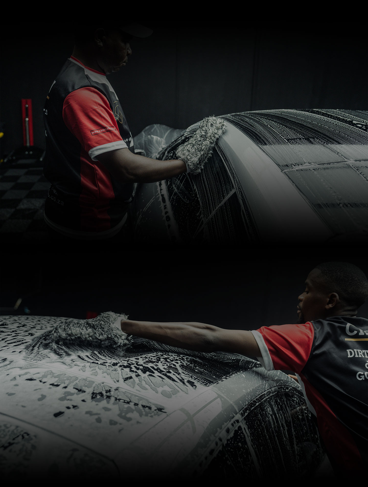 Two men washing a car covered in foam inside a dimly lit garage.