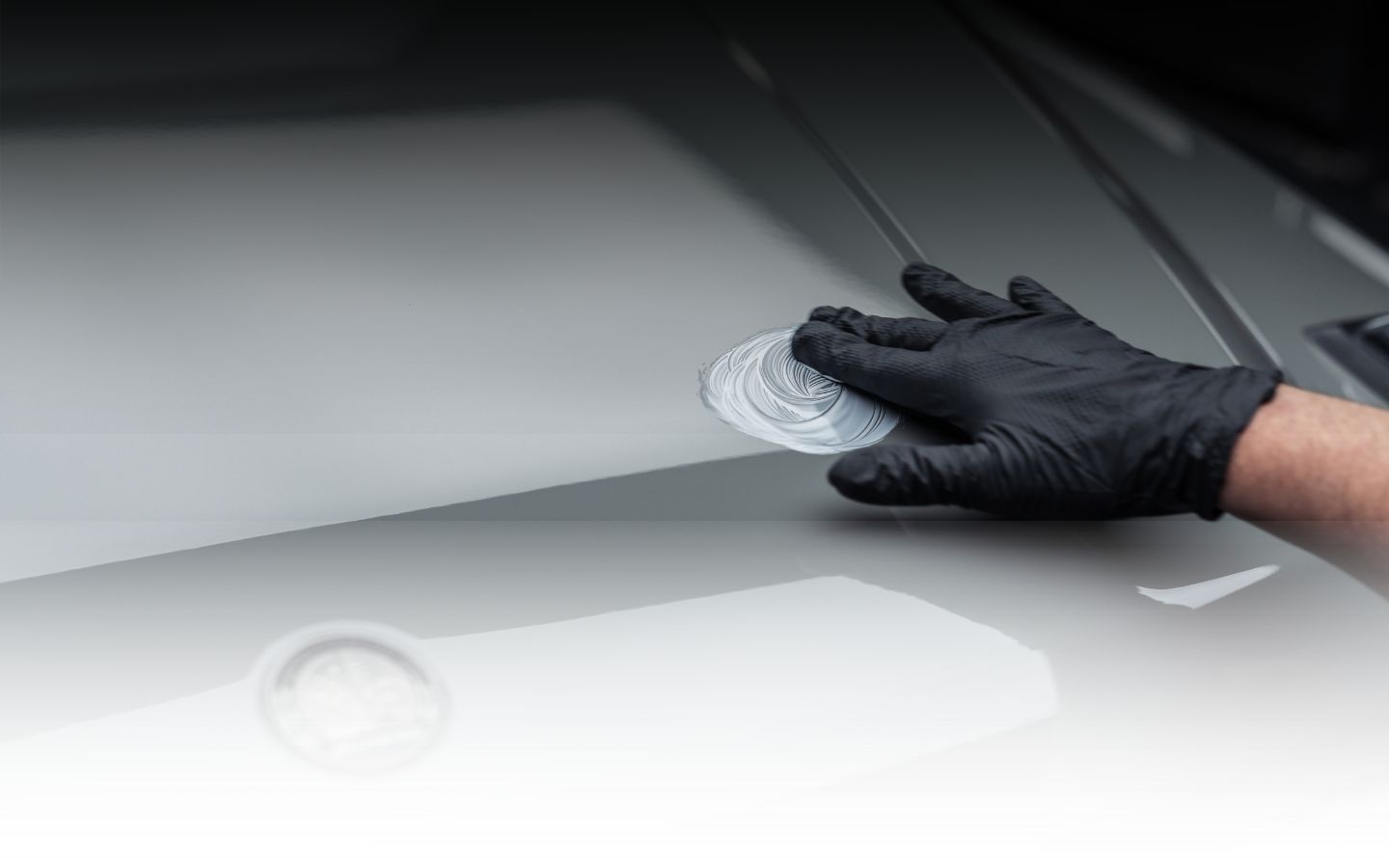 Man using foam cannon to apply thick white foam on a sports car during detailing.